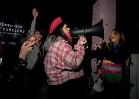 At the Live Action pro life candlelight vigil at Jackson Women's Health Center on Oct. 29, Kim Gibson (right), clinic escort and co-organizer of the Pink House Defenders, stands in front of the clinic as Terrisa Bukovinac (founder and Executive Director of the Progressive Anti-Abortion Uprising) uses a bullhorn to speak out against abortion