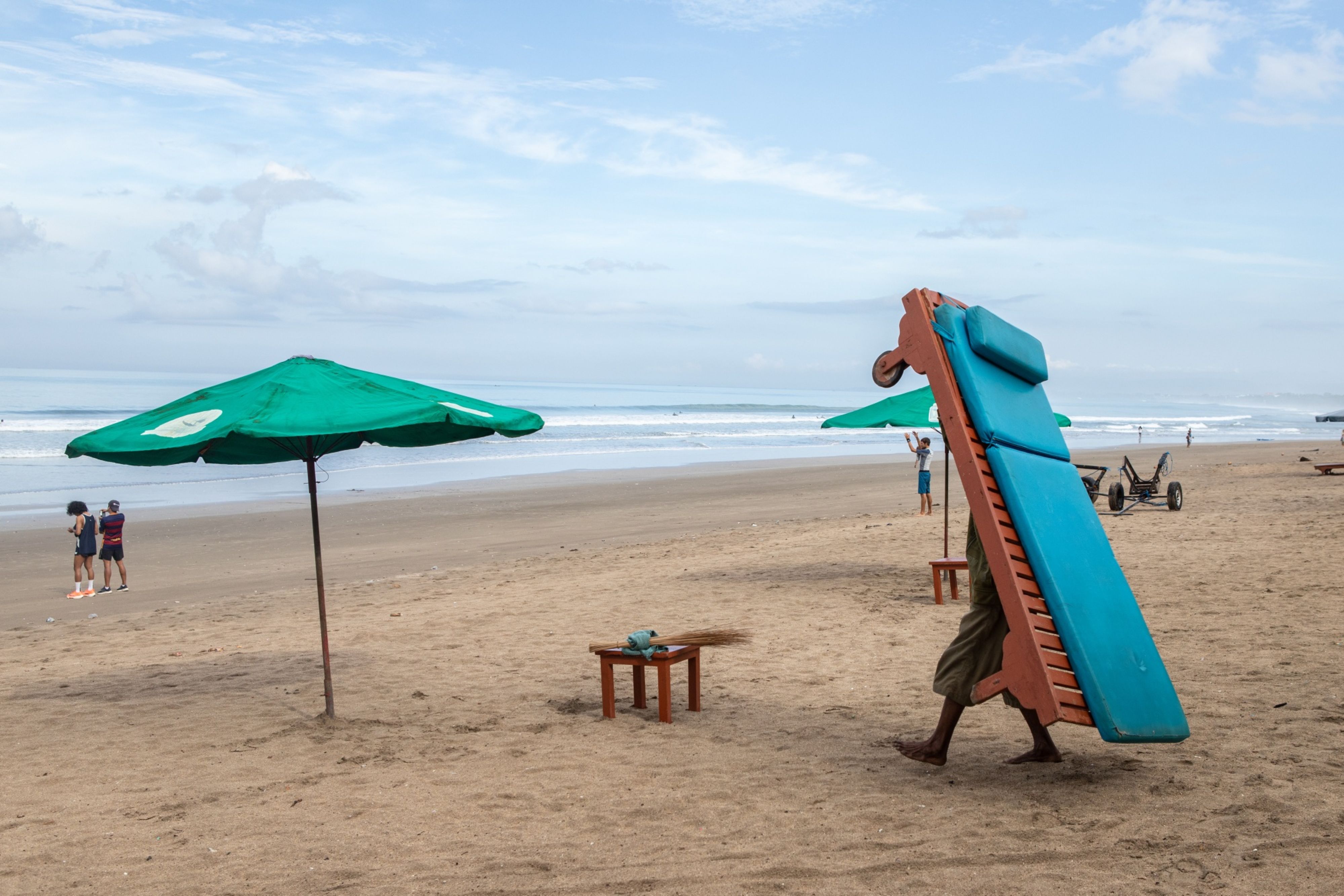 A man carries a lounge chair at the beach in the Kuta area of Bali, Indonesia, on Friday, Oct. 29, 2021. (© 2021 Bloomberg Finance LP)