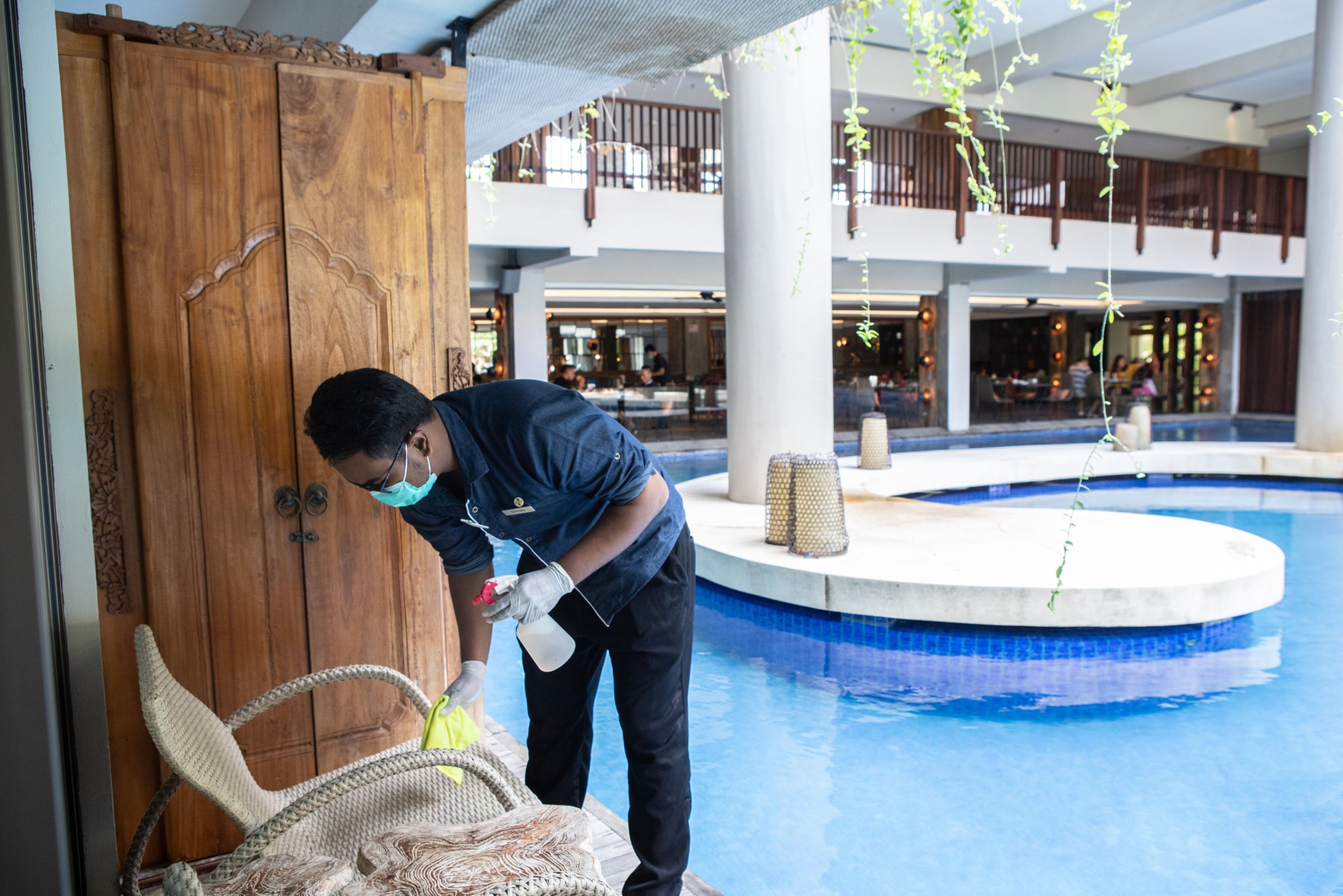 An employee wipes a chair by the swimming pool with disinfectant at Four Points By Sheraton Hotel in the Kuta area of Bali, Indonesia, on Friday, Oct. 29, 2021. (© 2021 Bloomberg Finance LP)