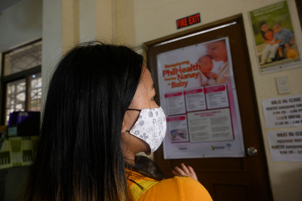 In this photo taken on December 2, 2020, Donna Valdez, 15, whose name AFP has changed to protect her identity, arrives with her child at a health center in Manila. (TED ALJIBE/AFP via Getty Images)