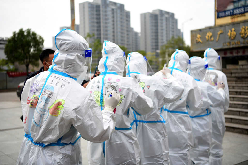Medical workers draw cartoons on each other's protective suits after finishing their work on COVID-19 nucleic acid testing, in Qianshan County, Shangrao, Jiangxi province, China, on Nov. 20, 2021 (Ding Minghua/VCG via Getty Images)