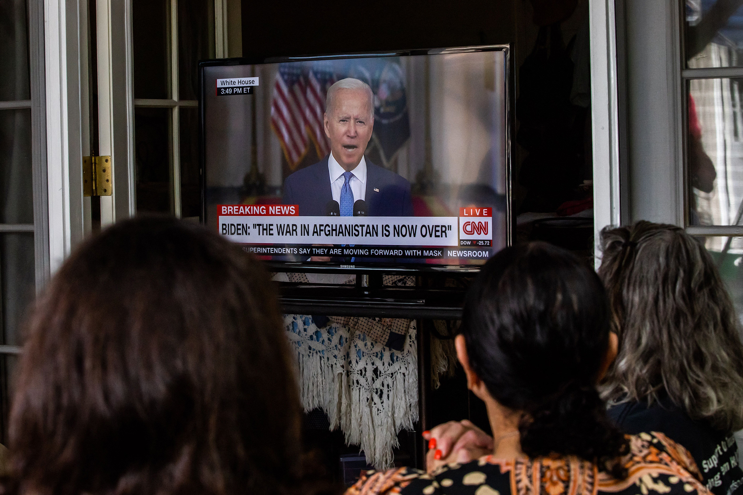 A group of military families and veterans watch President Joe Biden's speech announcing that all troops are out of Afghanistan, in Long Beach Calif., on Aug. 31, 2021.