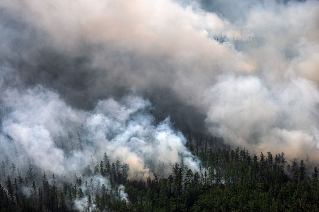 An aerial picture taken  on July 27, 2021, shows smoke rising from a forest fire outside the village of Berdigestyakh, in the republic of Sakha, Siberia, which lies within the Arctic circle. (Dimitar Dilkoff—AFP/ Getty Images)