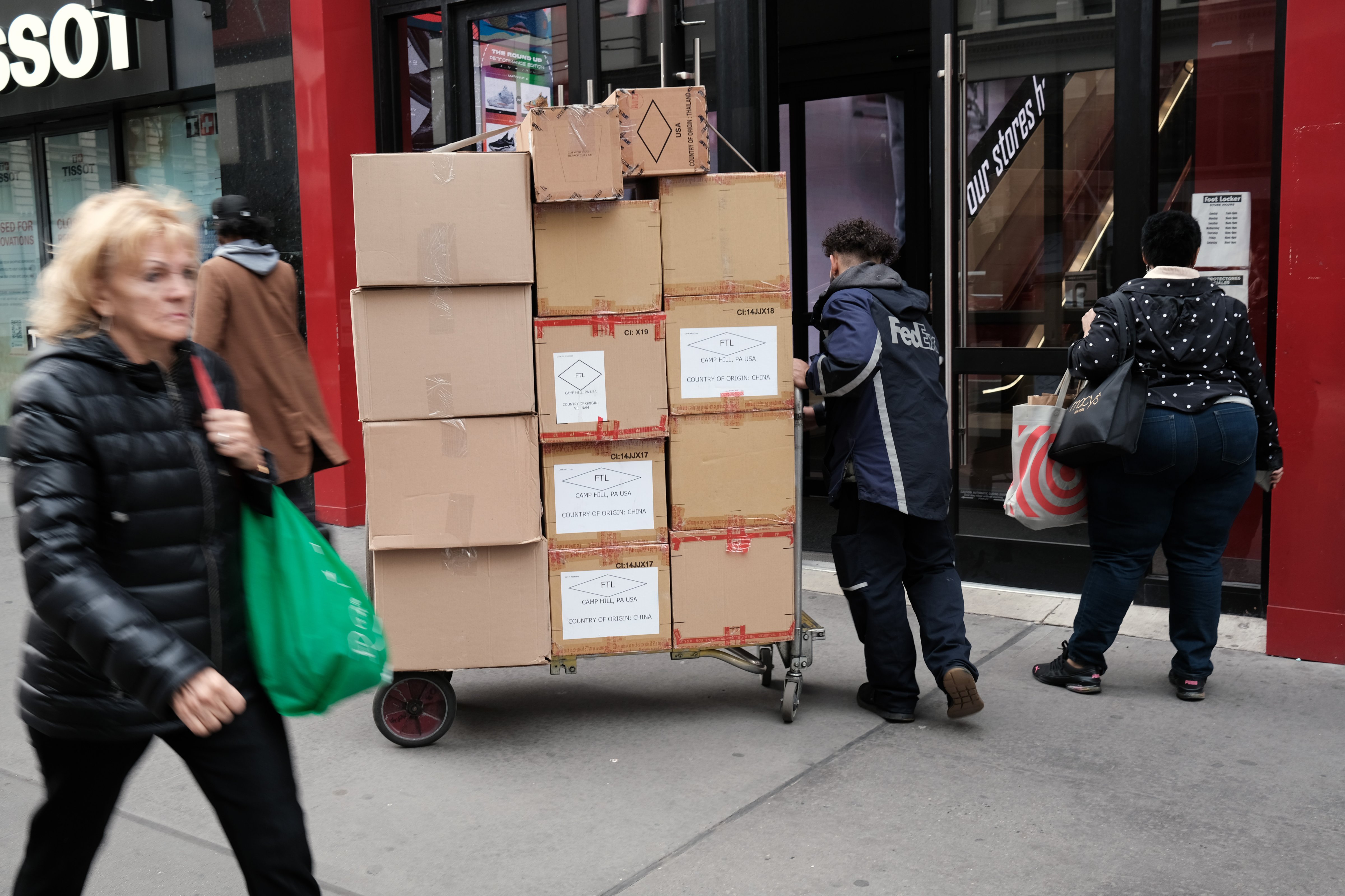 A FedEx worker pushes boxes of goods along a busy street in New York City on Nov. 17, 2021, at the start of the holiday shopping season. (Spencer Platt—Getty Images)