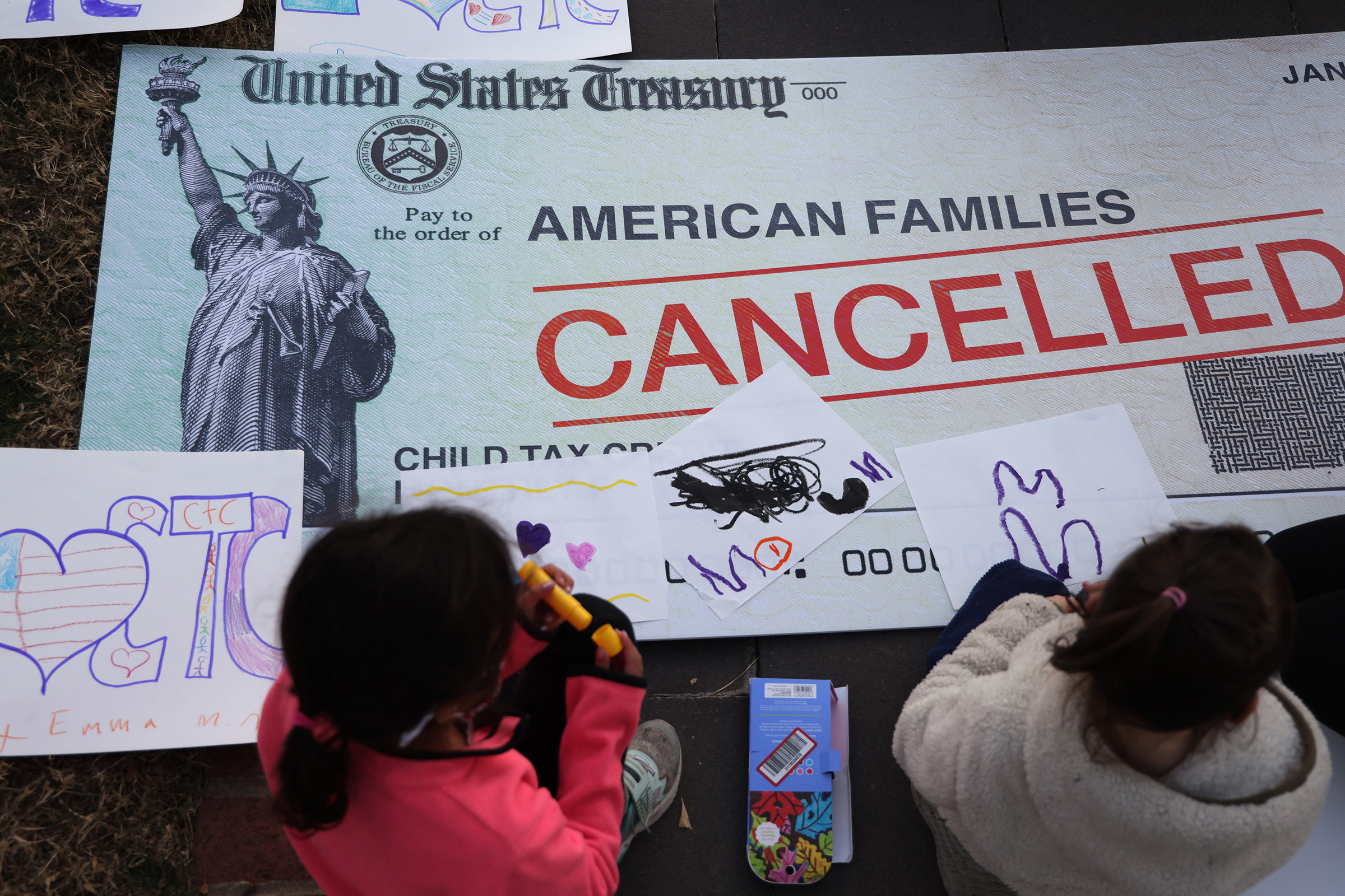 Children draw on top of a 'cancelled check' prop during a rally urging the passage of the Build Back Better legislation to extend the expanded Child Tax Credit, in front of the U.S. Capitol in Washington, D.C., on Dec. 13, 2021. (Alex Wong—Getty Images)