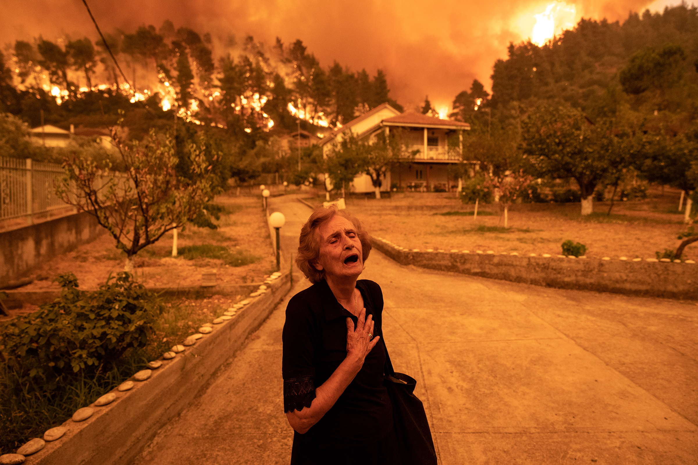 On the Greek island of Evia, wildfires spawned by the country’s worst heat wave in three decades approach the home of Ritsopi Panayiota, 81, on Aug. 8. (Konstantinos Tsakalidis—Bloomberg/Getty Images)