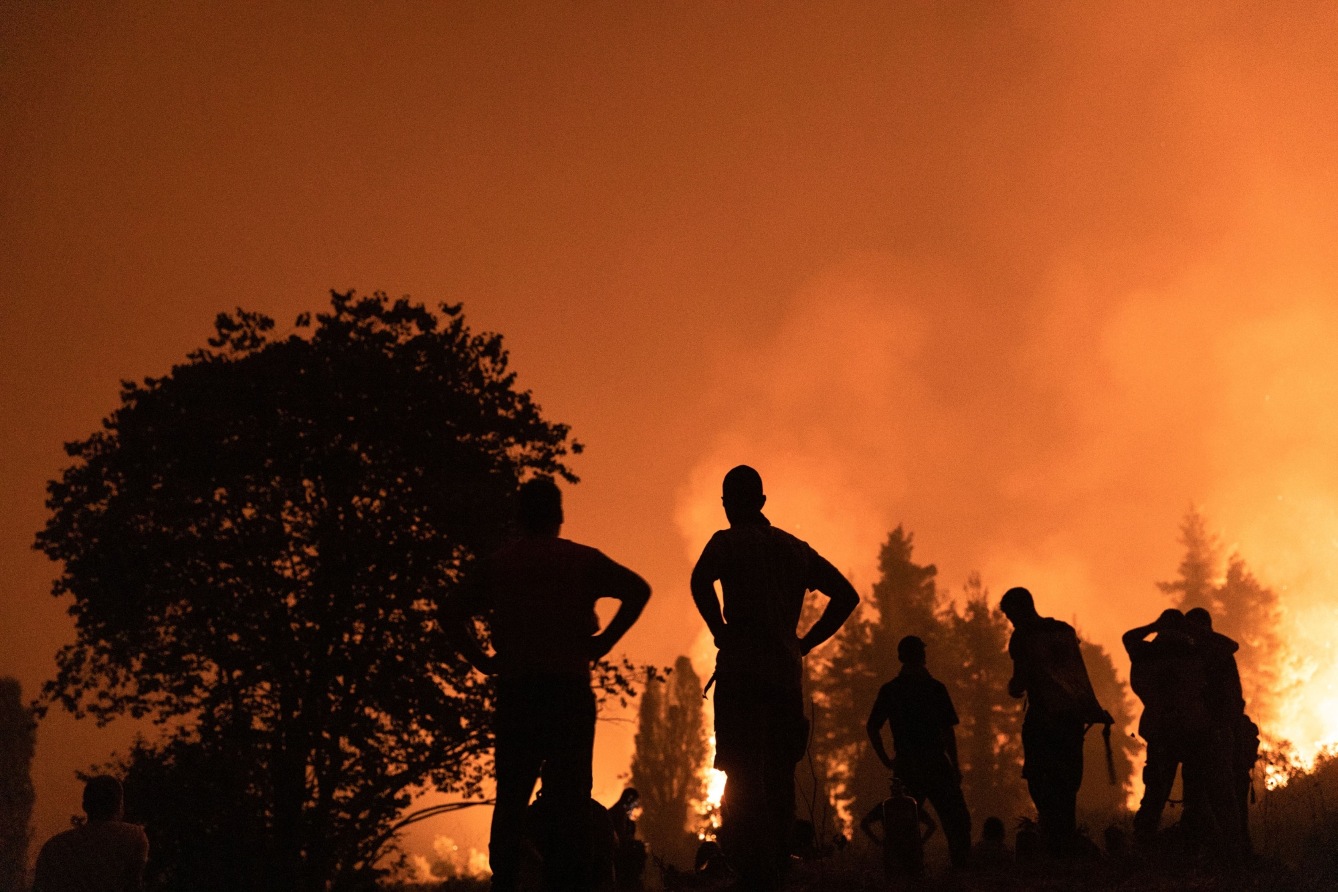 Residents watch over the wildfire outside the village of Kamatriades, on Evia island, Greece, on Aug. 9, 2021. (Konstantinos Tsaka—Bloomberg)