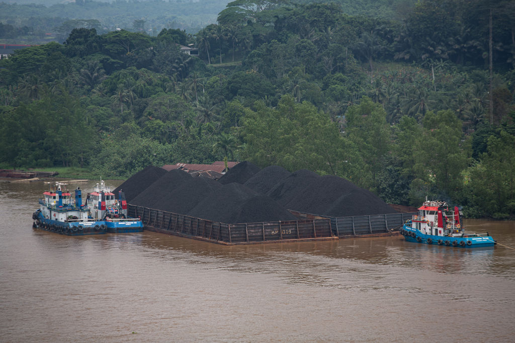 A tugboat sails past piles of coal on a barge on the Mahakam River in Samarinda, East Kalimantan, Indonesia on October 15, 2021. (Afriadi Hikmal&mdash;NurPhoto/Getty Images)