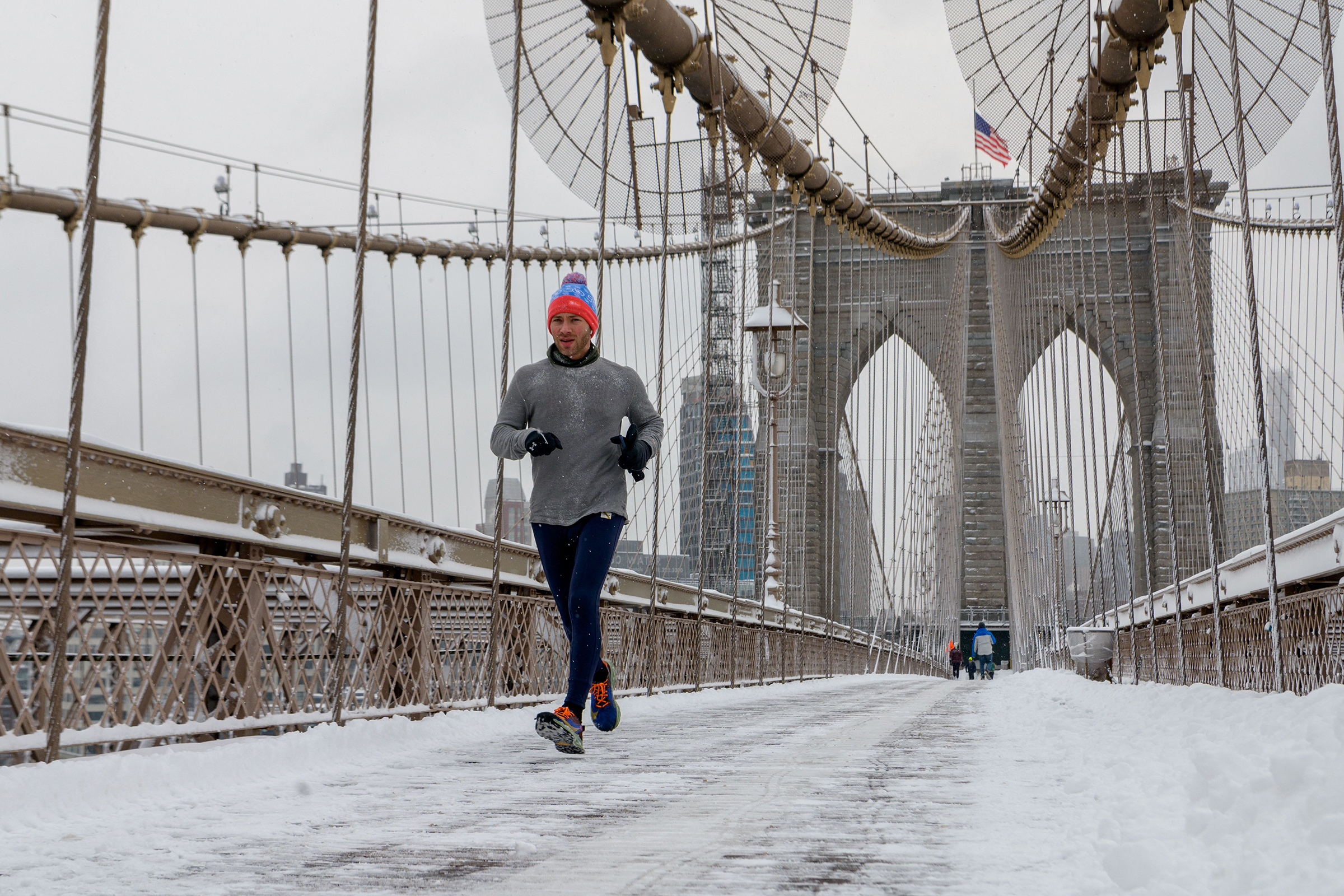 A runner crosses the Brooklyn Bridge during the first snow storm of the season on January 7, 2022 in New York City. (Angela Weiss—AFP/Getty Images))