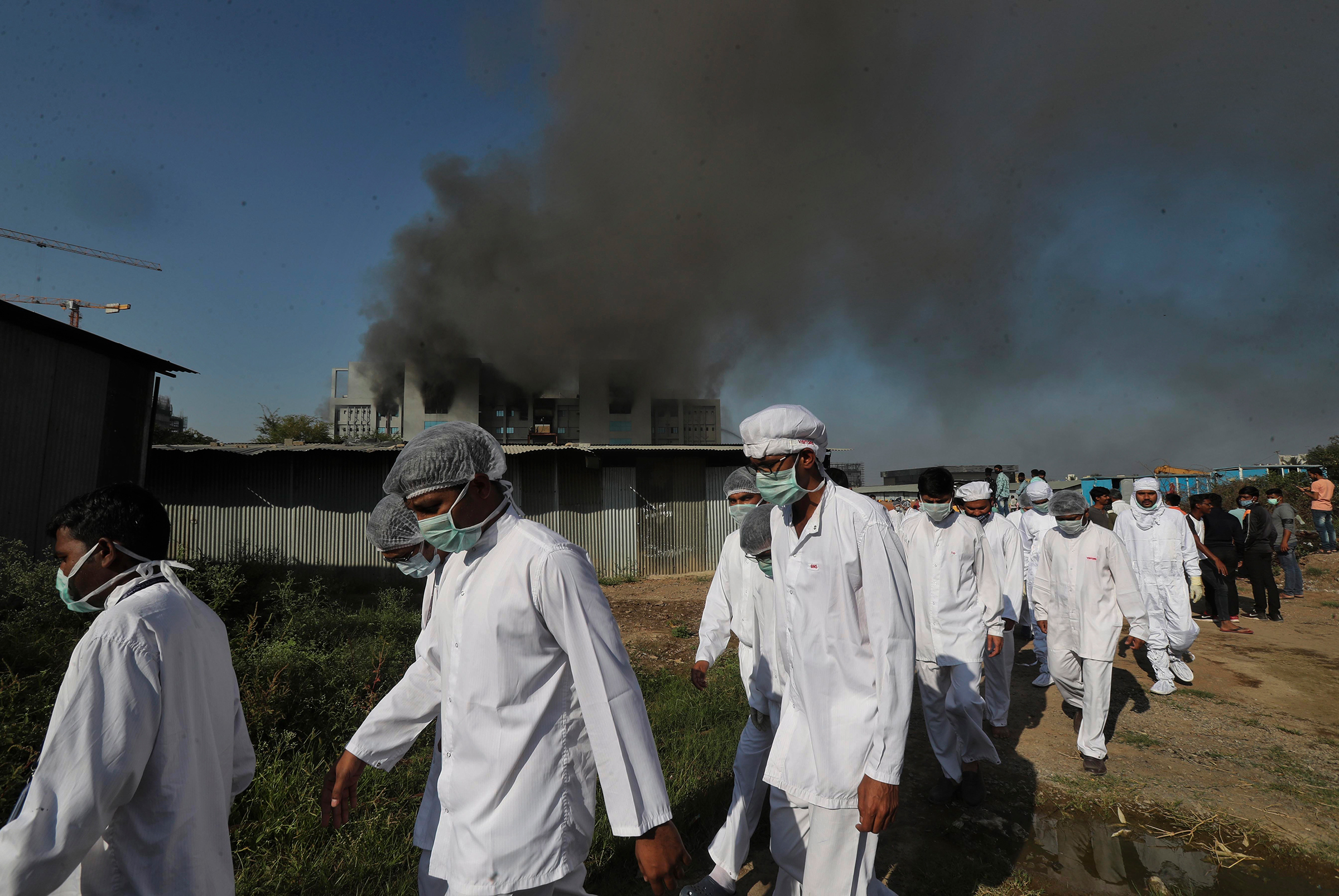 Employees leave as smoke rises from a fire at Serum Institute of India, Pune, on Jan. 21, 2021