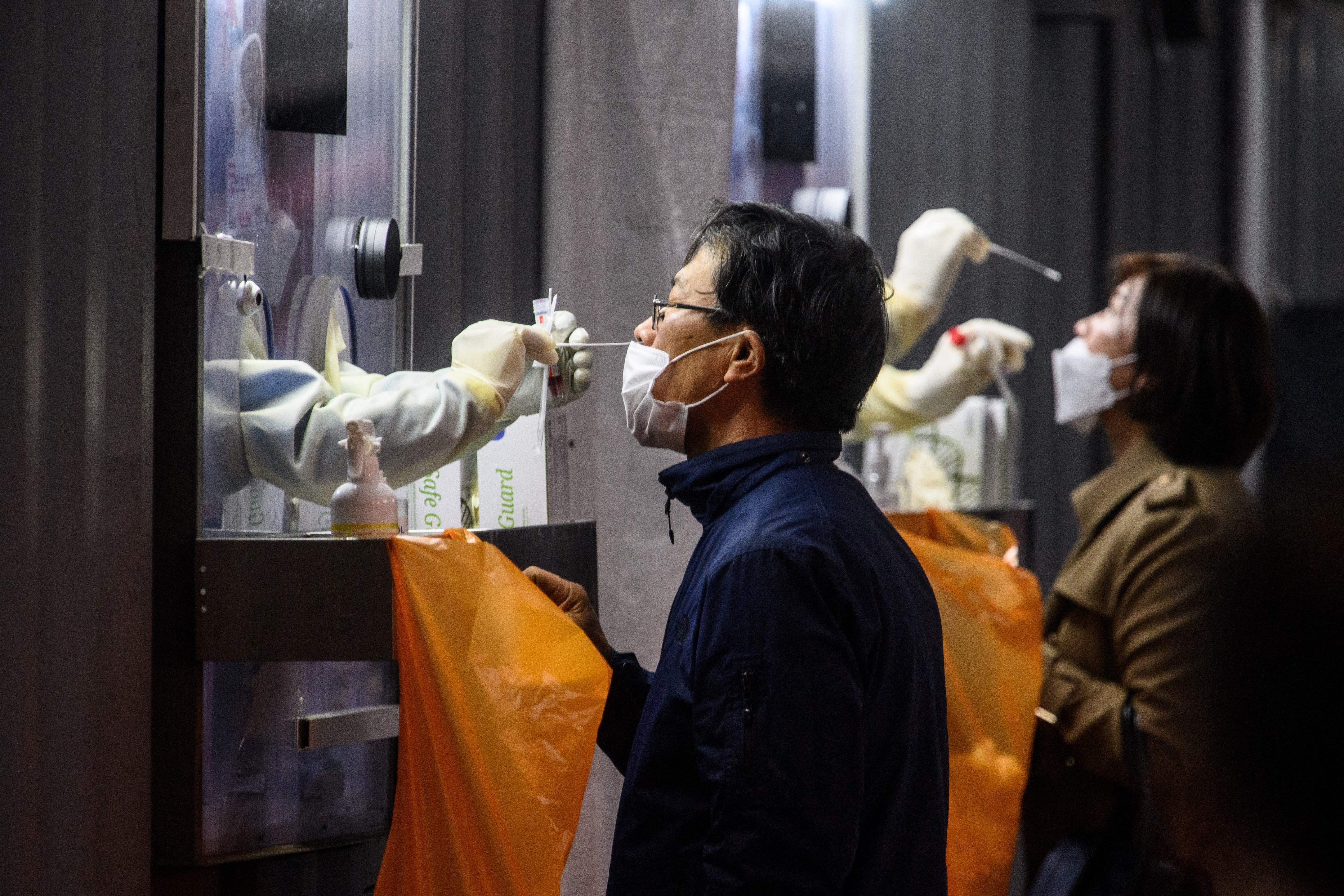 A man and woman undergo PCR (polymerase chain reaction) tests at a Covid-19 coronavirus testing centre in Seoul on November 3, 2021. (Anthony Wallace/AFP via Getty Images)
