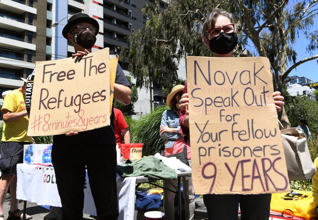 Activists hold placards during a rally outside a government detention centre where Serbia's tennis champion Novak Djokovic is staying in Melbourne on January 9, 2022, in support of refugees detained at the centre. (William West—AFP/Getty Images)