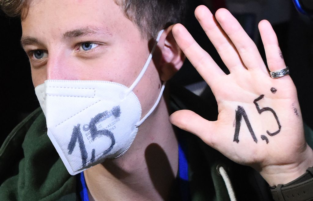 An activist with 1.5 written on their hand and face mask—representing the goal to limit global temperature rise to 1.5°C above preindustrial levels—demonstrating at the COP26 U.N. Climate Change Conference in Glasgow on Nov. 10, 2021. (Andy Buchanan—AFP/Getty Images)