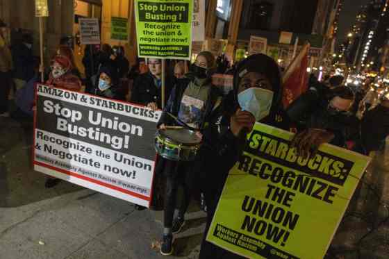 Orang-orang berbaris selama protes untuk mendukung pekerja Amazon dan Starbucks di New York City pada 26 November 2021. 