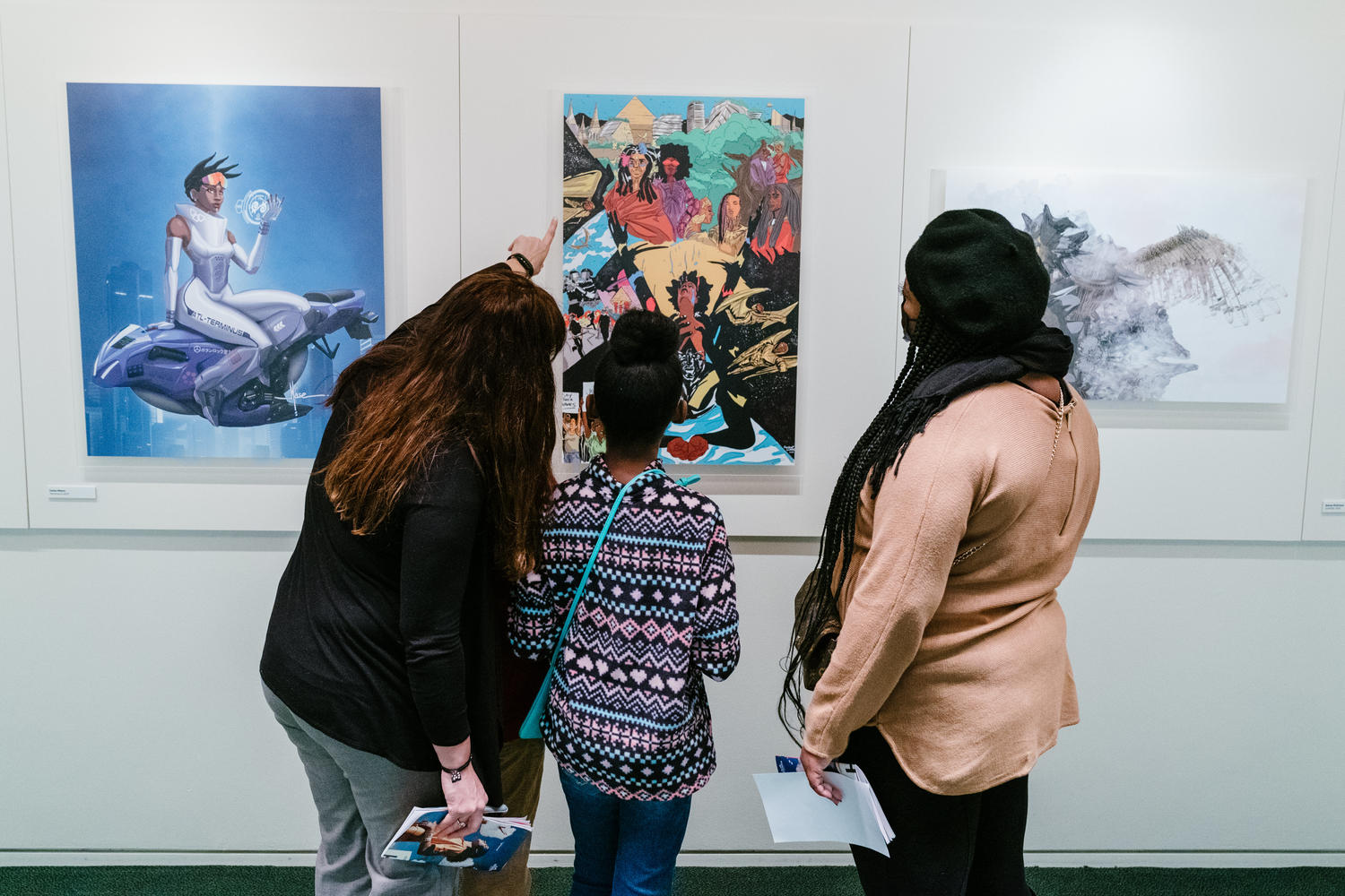 Visitors at an Afrofuturism exhibit at Carnegie Hall's Zankel Hall Gallery, in Feb. 2022 in New York City.
                      
                      Artwork (left to right):
                      1. Terminus 2 by James Mason
                      2. All Possible Future by Alan Saint Clark
                      3. Atoms of an Evening Wing by Quentin VerCetty (Fadi Kheir)