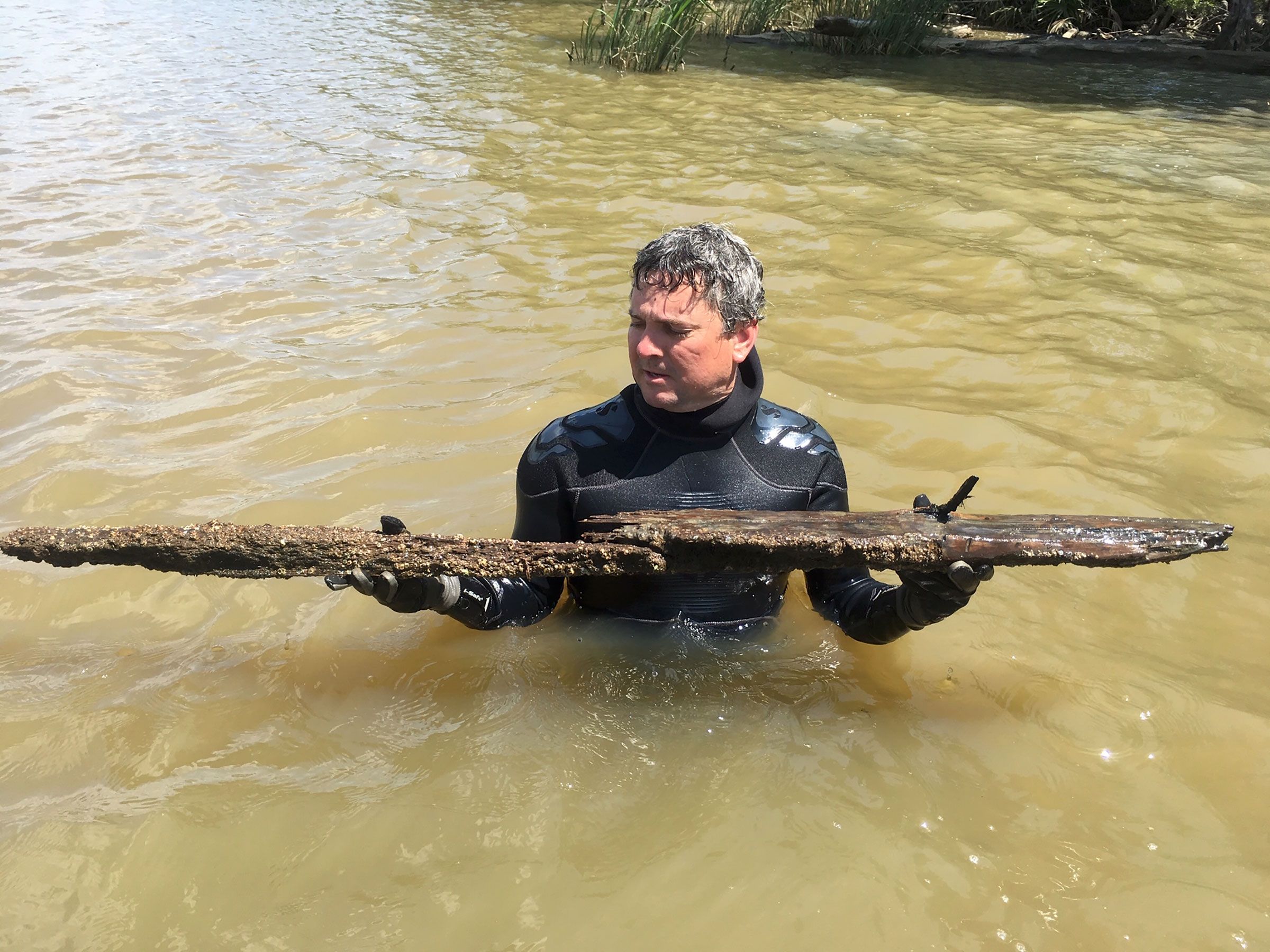 Ben Raines holds a piece of the Clotilda after Raines and a team from the University of Southern Mississippi discovered the wreck, April 2018. (Courtesy Joe Turner)