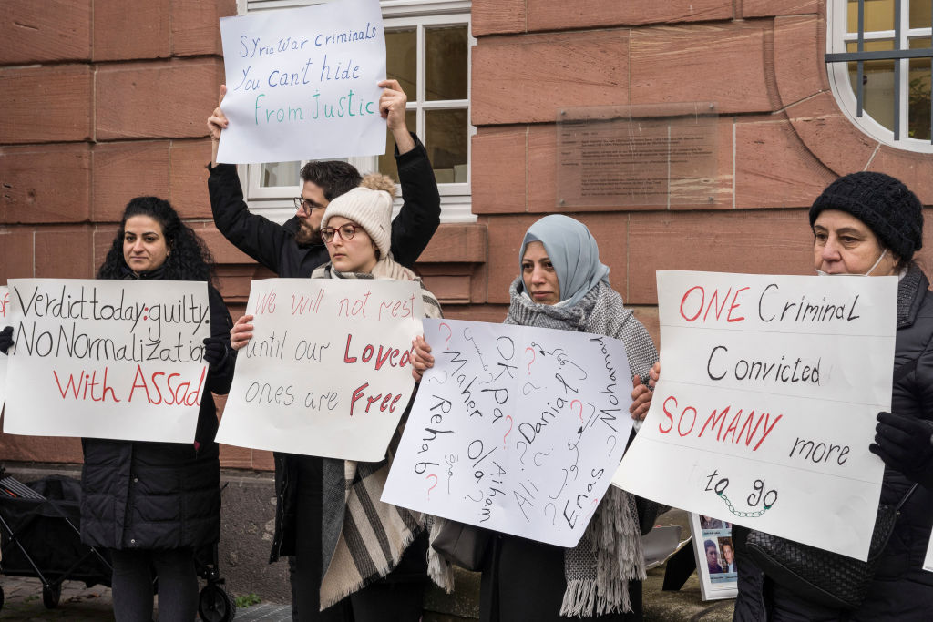 People hold posters during a demonstration outside the courthouse where former Syrian intelligence officer Anwar Raslan stood on trial in Koblenz, Germany, on Jan. 13, 2022 (Bernd Lauter—AFP/Getty Images)