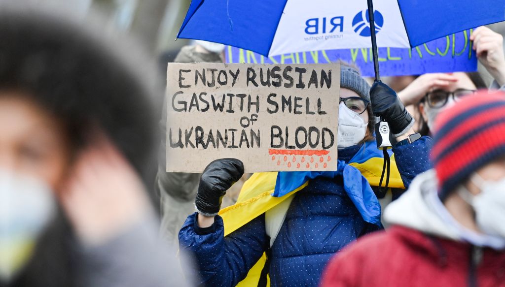 A demonstrator holds a placard reading "Enjoy Russian gas with smell of Ukrainian blood" during a protest against Russia's invasion of the Ukraine on February 25, 2022 in front of the Chancellery in Berlin. (John MACDOUGALL-AFP)