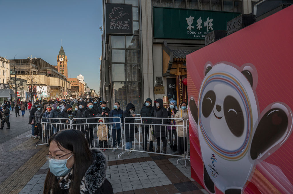 A poster shows mascot Bing Dwen Dwen as people line up outside the official Beijing 2022 Winter Olympics flagship souvenir store on February 8, 2022 in Beijing, China. (Kevin Frayer/Getty Images)