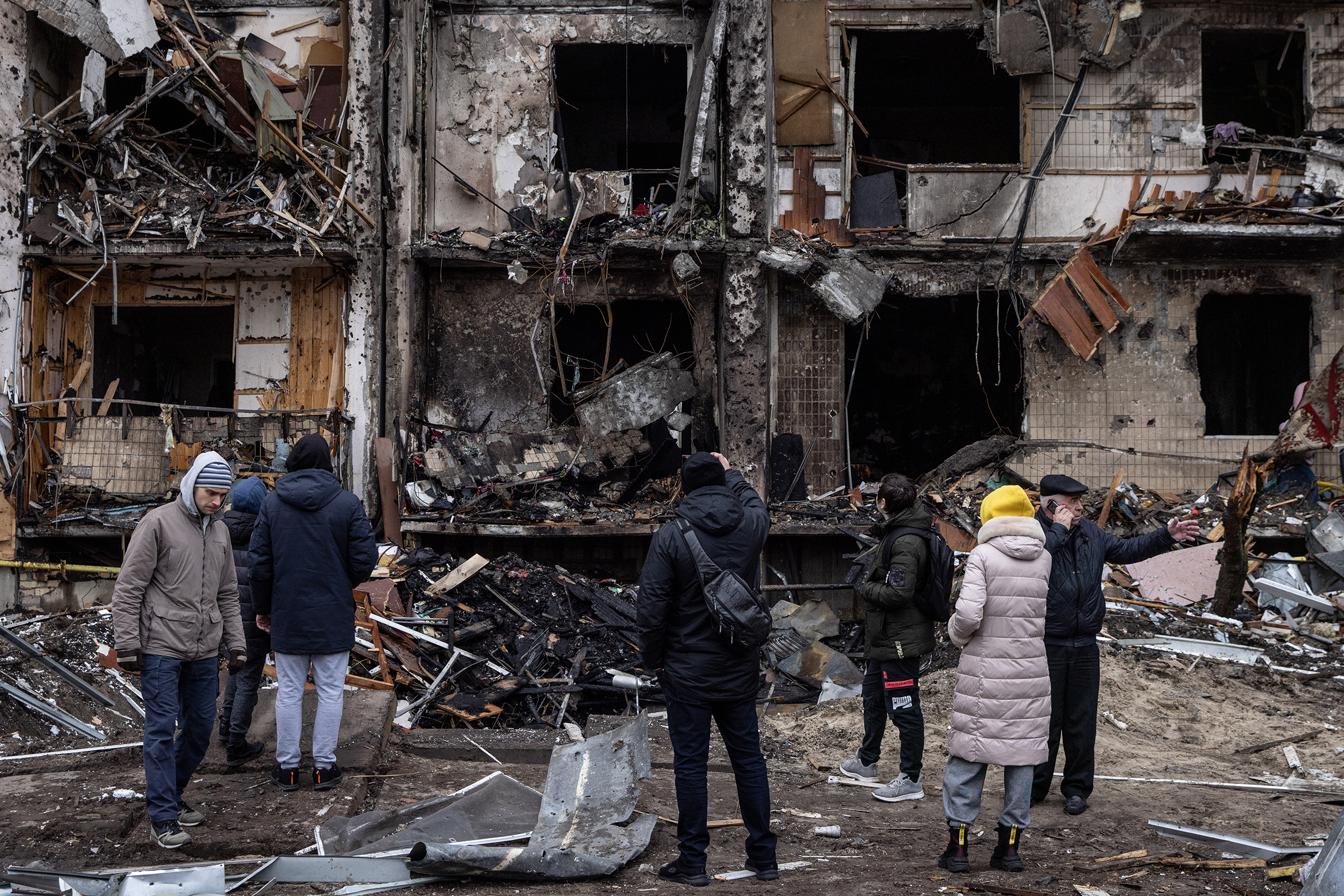 People look at the exterior of a damaged residential block hit by an early morning missile strike on February 25, 2022 in Kyiv, Ukraine. (Chris McGrath—Getty Images)