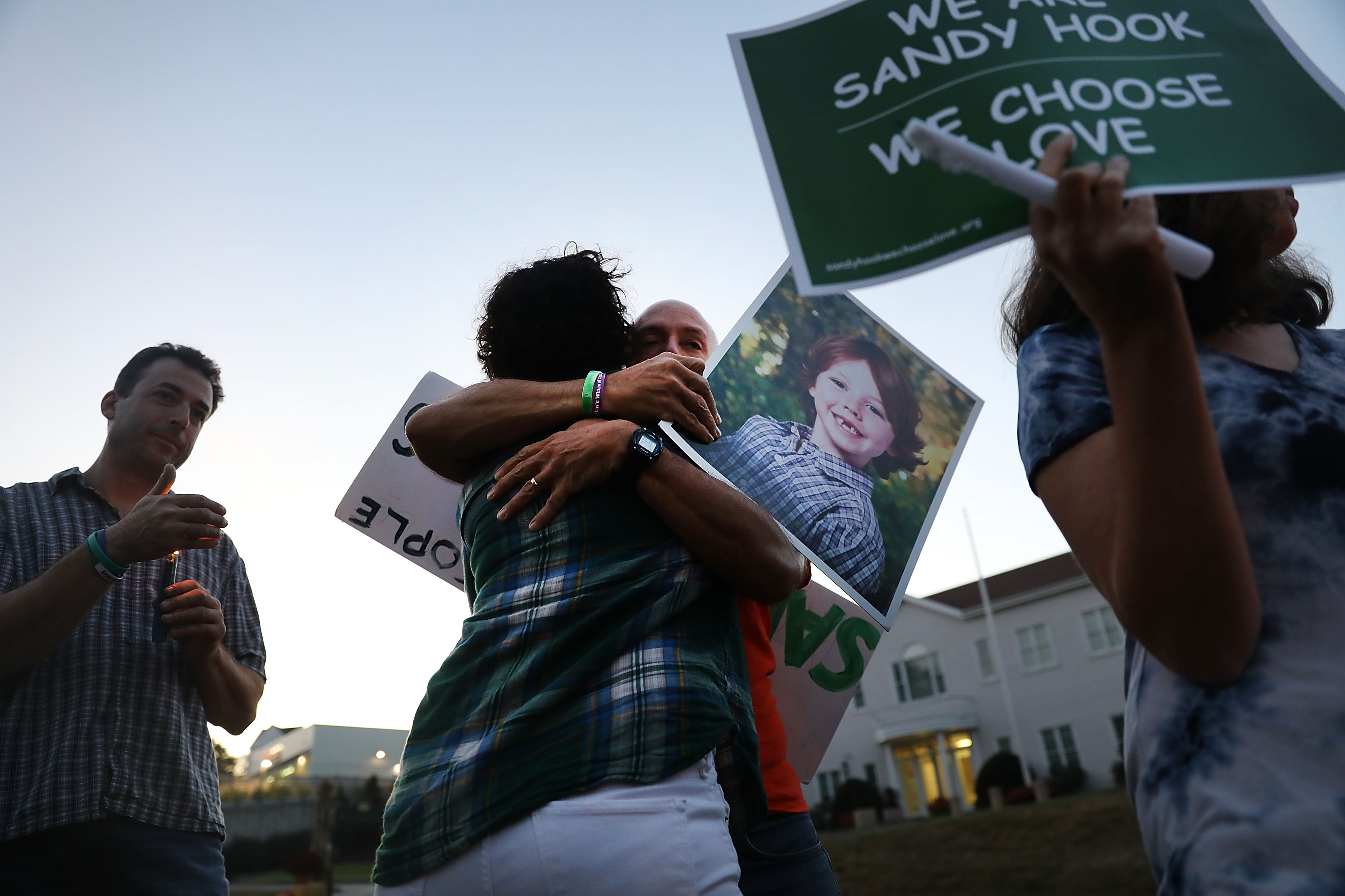 Mark Barden gets a hug while holding up a picture of his son, Daniel, who was killed in the Sandy Hook school shooting, during a vigil in Newtown, Conn., on Oct. 4, 2017 to honor victims of a Las Vegas mass shooting. (Spencer Platt—Getty Images)