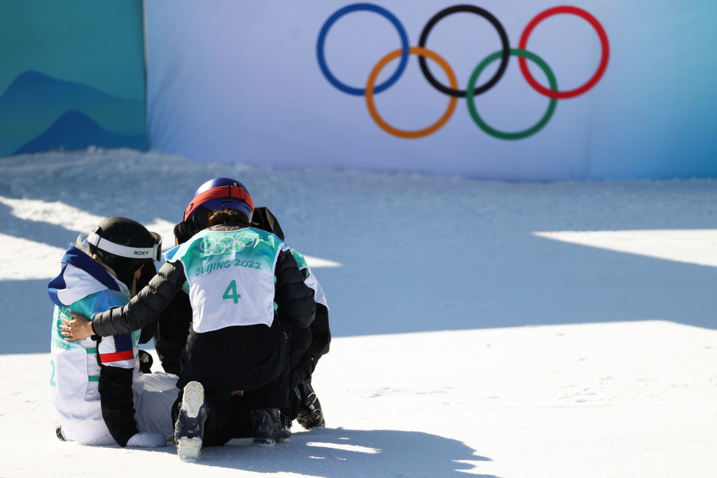 Bronze medalist Mathilde Gremaud of Switzerland and Ailing Eileen Gu of China console silver medalist Tess Ledeux of Team France after the women's freestyle skiing freeski big air final at the Beijing Winter Olympics.