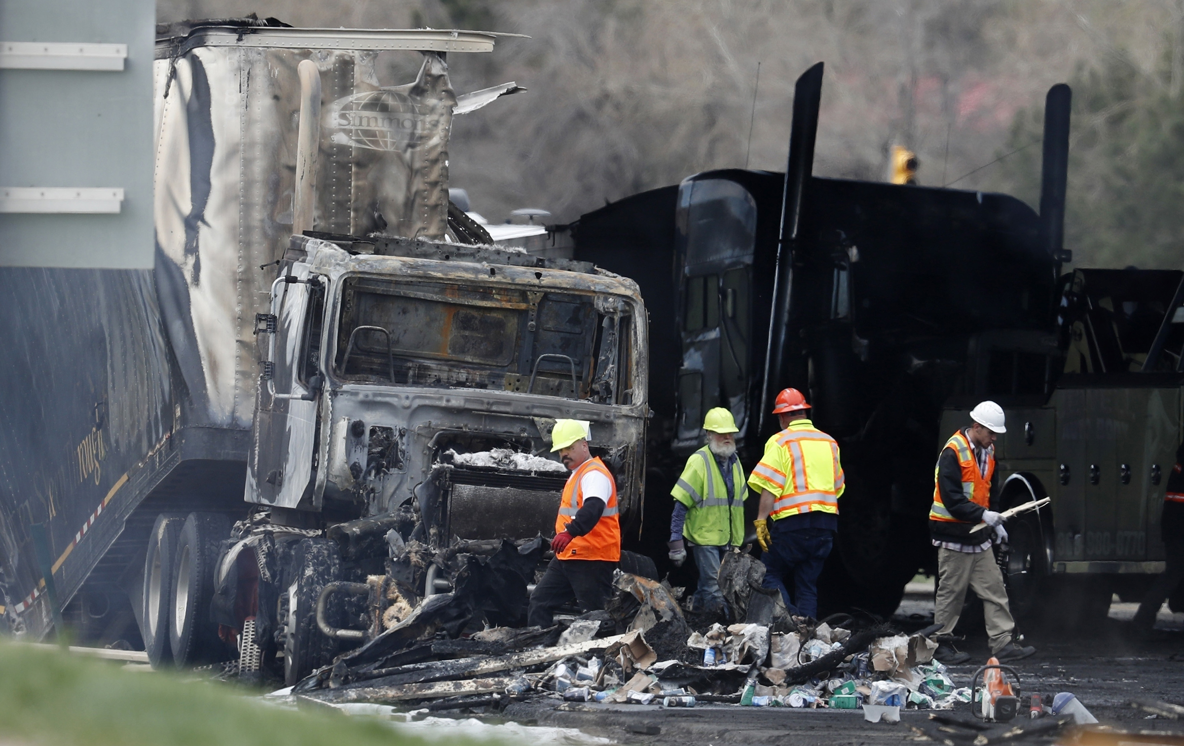 Workers clear debris from Interstate 70 on April 26, 2019, in Lakewood, Colo., following a deadly pileup involving a semi-truck hauling lumber. The truck driver who was convicted of causing the fiery pileup that killed four people said he had no experience navigating mountain roads; his 110-year sentence was later reduced to 10 years. (David Zalubowski—AP)