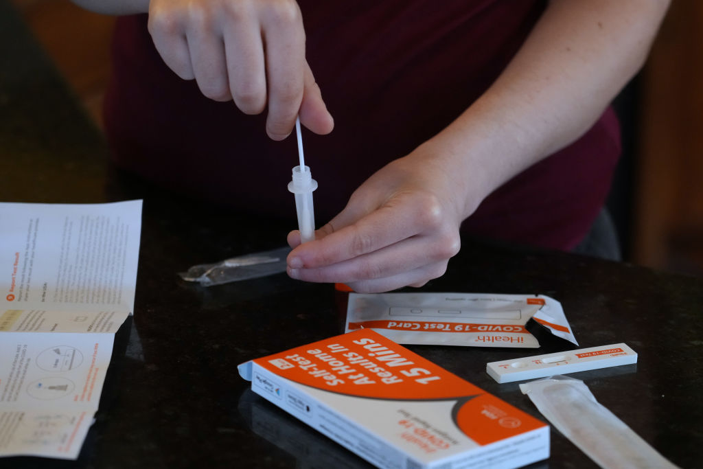 A woman processes a nasal swab in one of the government-issued COVID-19  test kits she received as she self tests while at home in Utah on Feb. 8, 2022. (George Frey—Getty Images)
