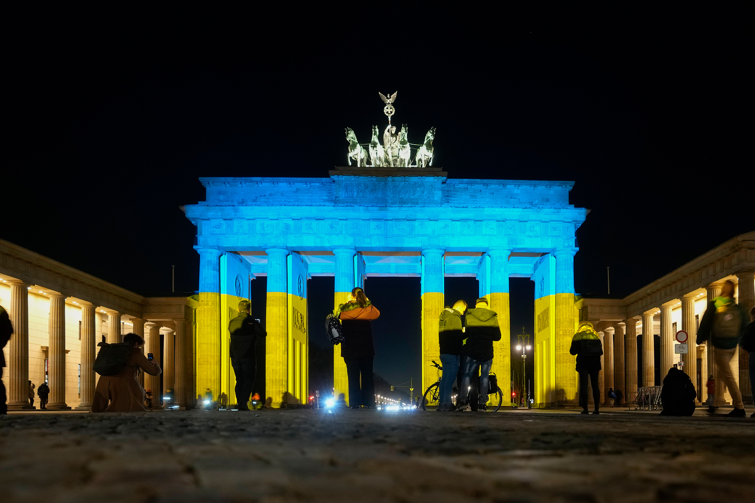 People look at the Brandenburg Gate after it was illuminated in the colors of the Ukrainian flag to show solidarity with the country during the tensions with Russia in Berlin, Feb. 23 (Markus Schreiber—AP)