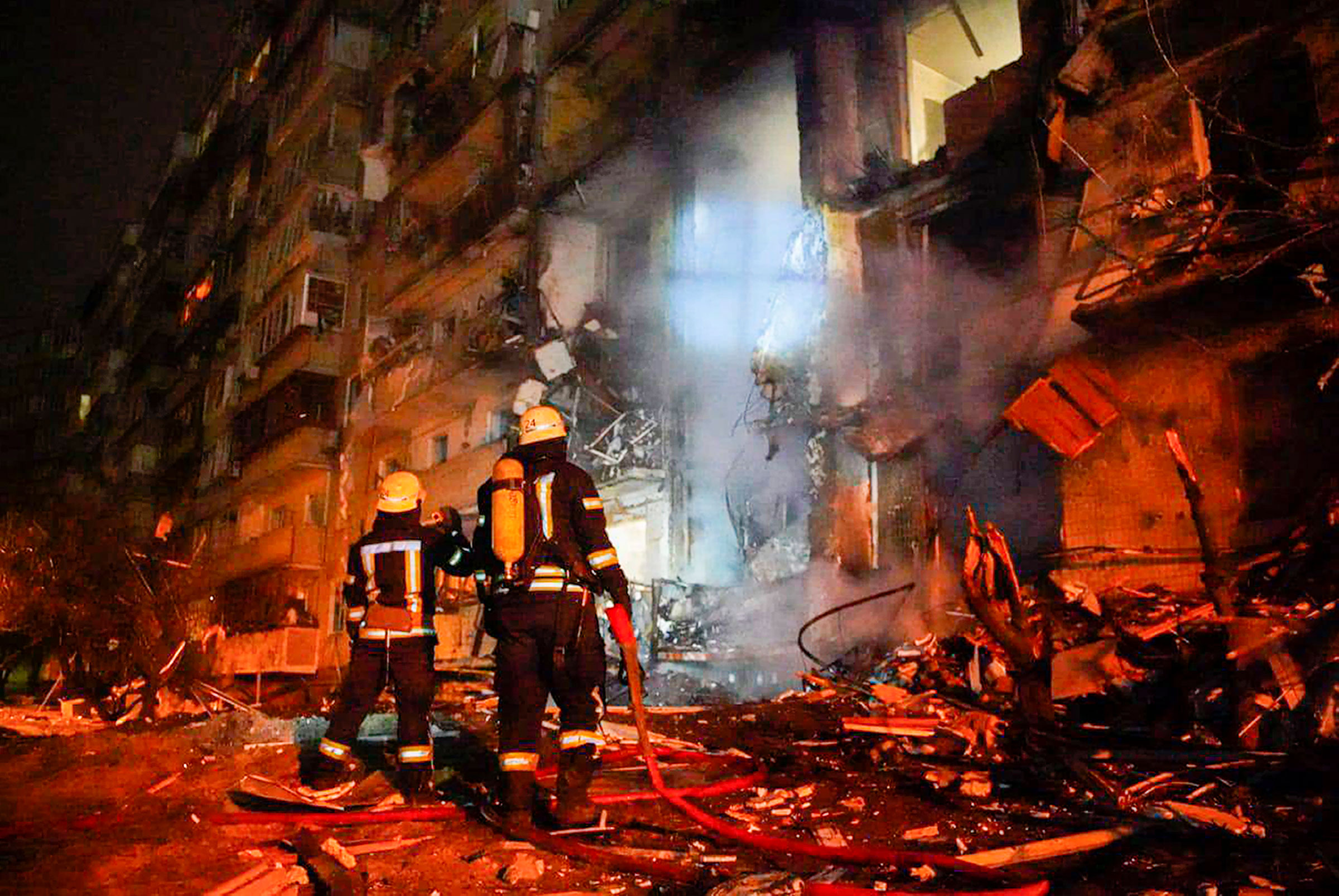 In this screen-grab, from a video released by Ukrainian Police Department Press Service, firefighters inspect the damage of a building following a missile attack on the city of Kyiv, on Feb. 25. (Ukrainian Police Department Press Service/AP)