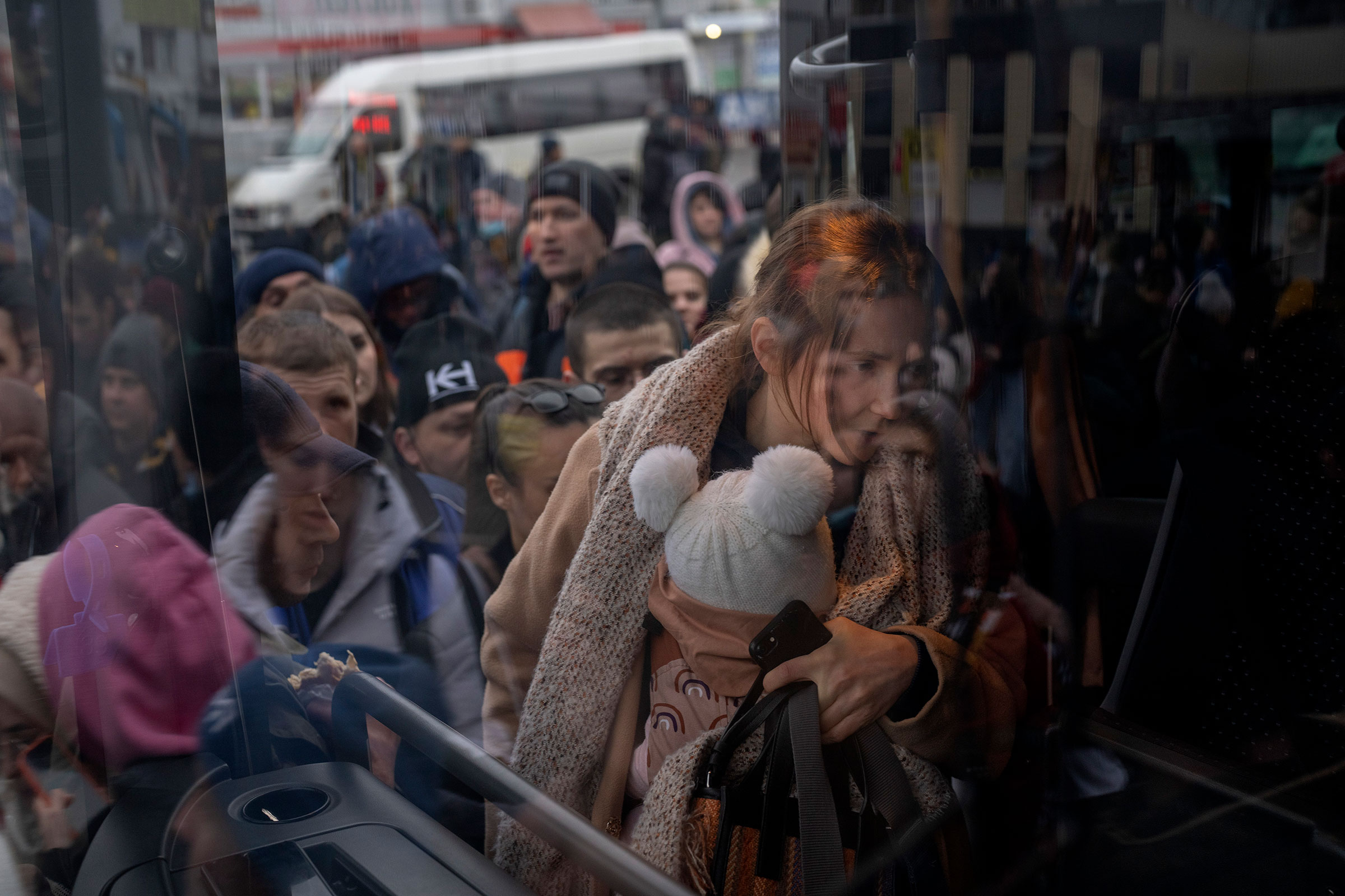 A woman holds her baby as she gets on a bus leaving Kyiv on Feb. 24. (Emilio Morenatti—AP)
