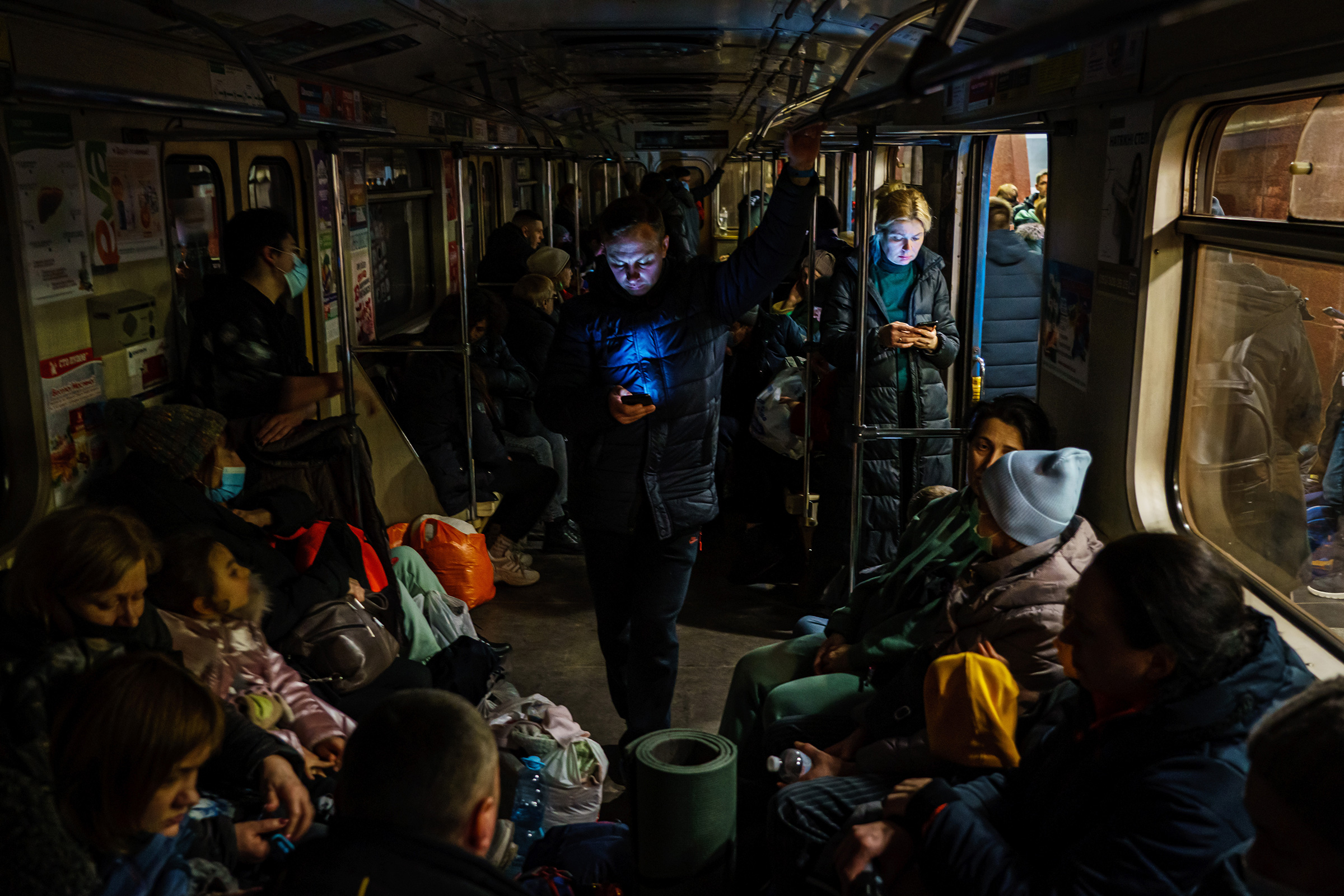 Hundreds of people seek shelter underground inside the dark train cars of a metro station in Kharkiv, as the Russian invasion of Ukraine continues on Feb. 24