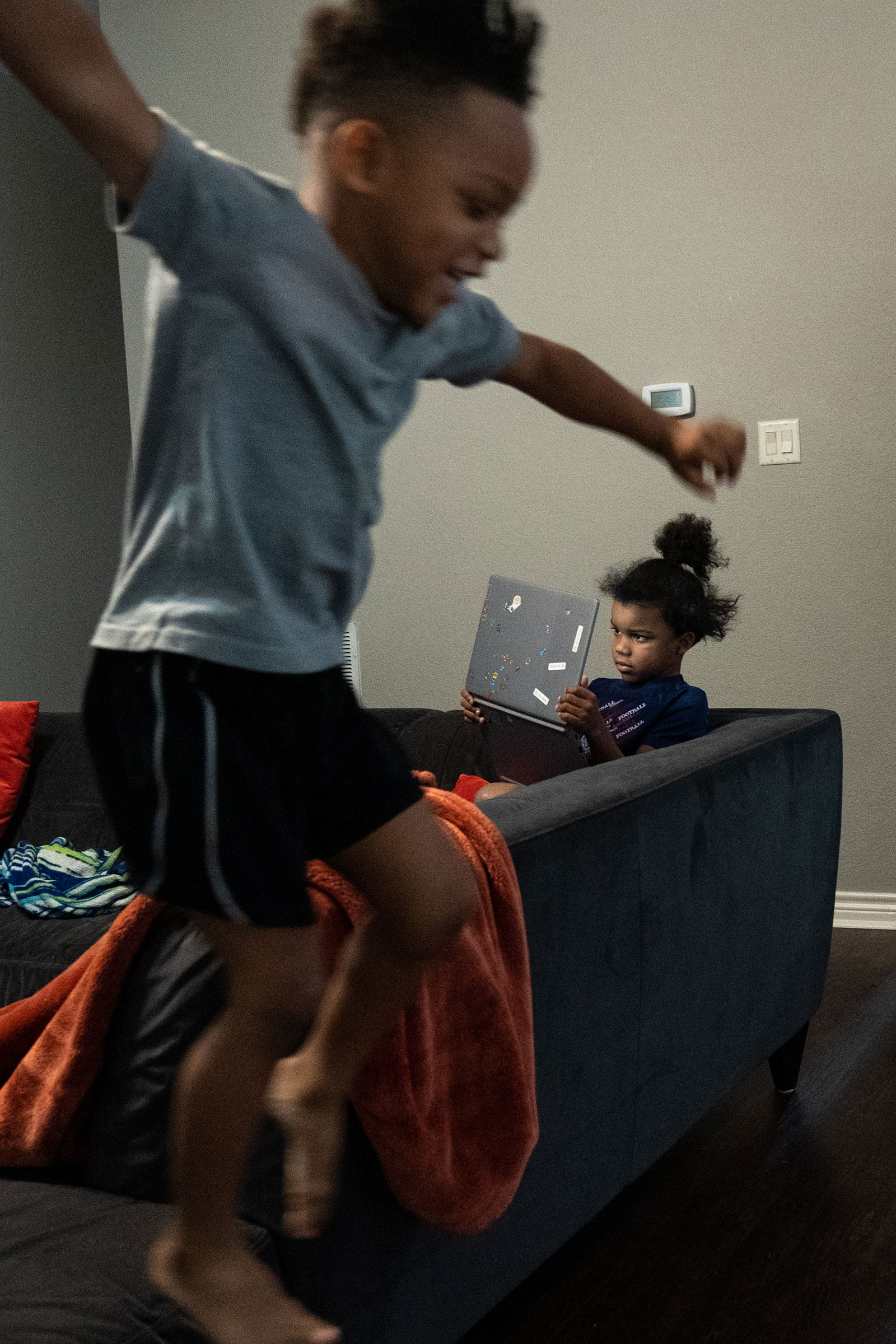 RICHARDSON, TEXAS - February 23, 2022: Brax, 6, studies his laptop as his younger brother Blaine, 4, jumps off the sofa. Ilana Panich-Linsman for TIME