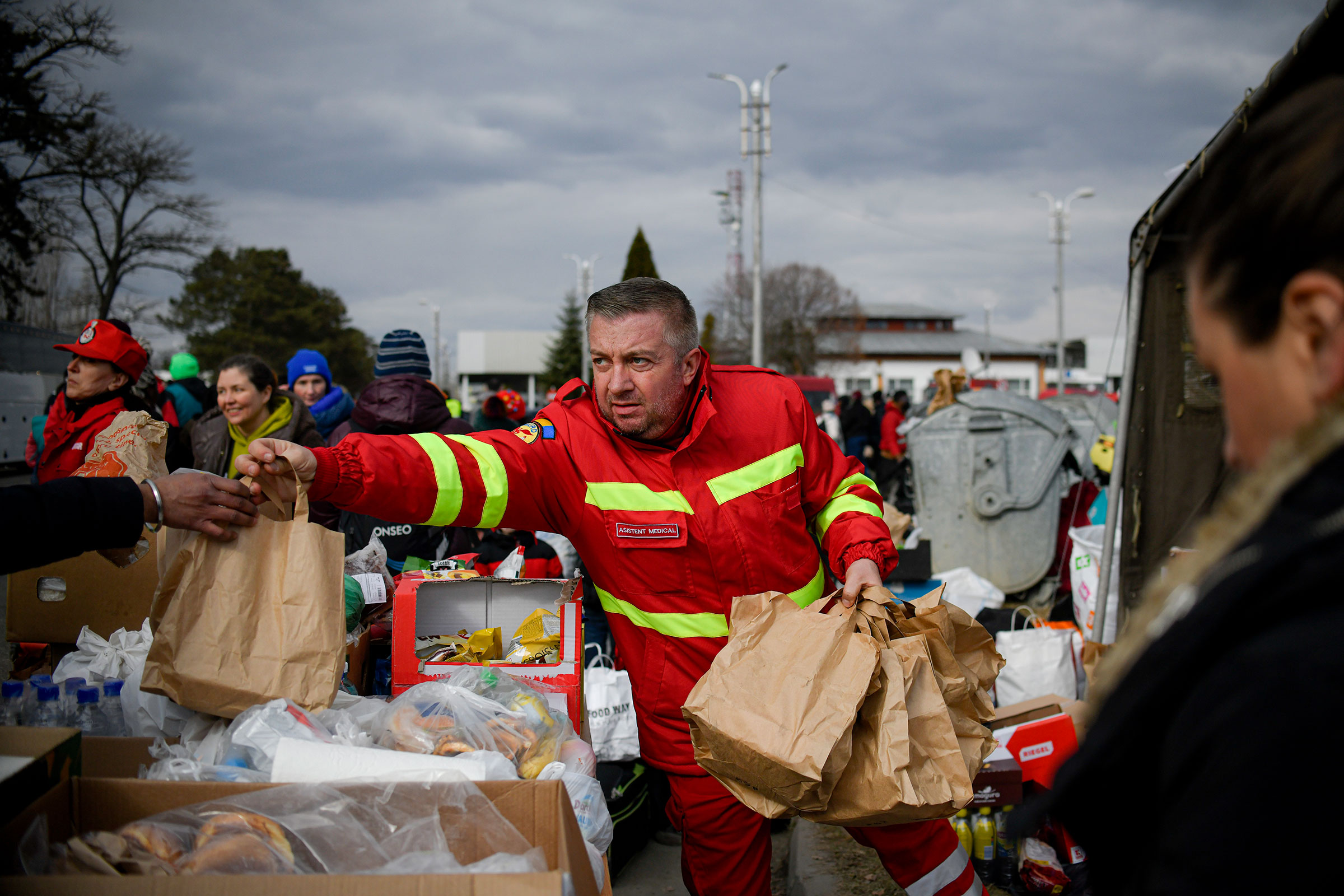 An employee of the Mobile Emergency Service for Resuscitation and Extrication, SMURD, hands out bags of food to refugees that fled the conflict from Ukraine at the Romanian-Ukrainian border, on Feb. 27, 2022. (Andreea Alexandru—AP)