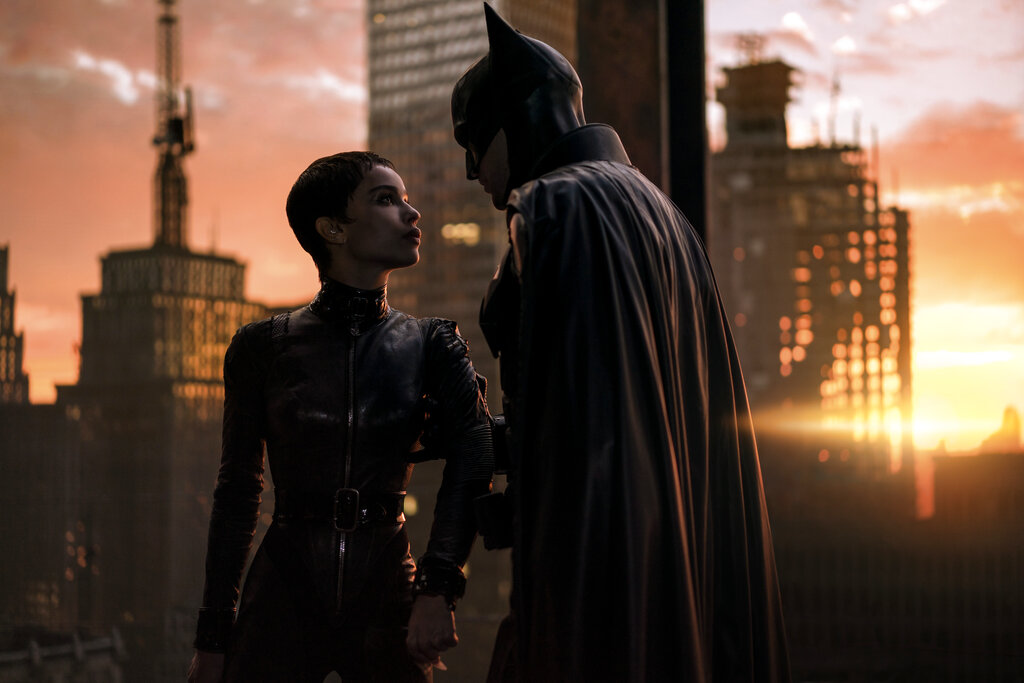 This image released by Warner Bros. Pictures shows Zoe Kravitz, left, and Robert Pattinson in a scene from "The Batman."  “The Batman” is still going strong three weeks into its theatrical run, with a tight grip on the top spot at the box office. Robert Pattinson’s debut as the Dark Knight earned an additional $36.8 million over the weekend, according to studio estimates Sunday, March 20, 2022. It also slid past the $300 million mark ahead of projections. (Jonathan Olley—Warner Bros. Pictures/AP)