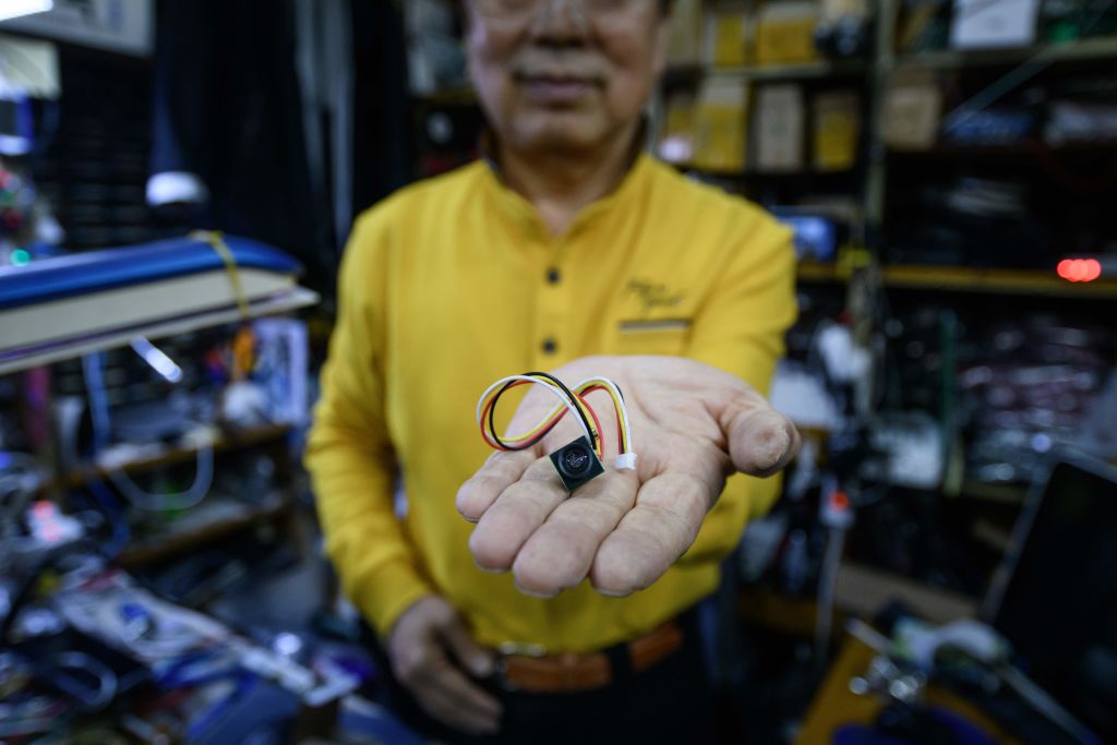In a photo taken on March 26, 2019 electrical component vendor and technician Lee Seung-yon holds a mini camera unit capabale of being built into custom-made devices, at his store in a market in Seoul. (ED JONES/AFP via Getty Images)