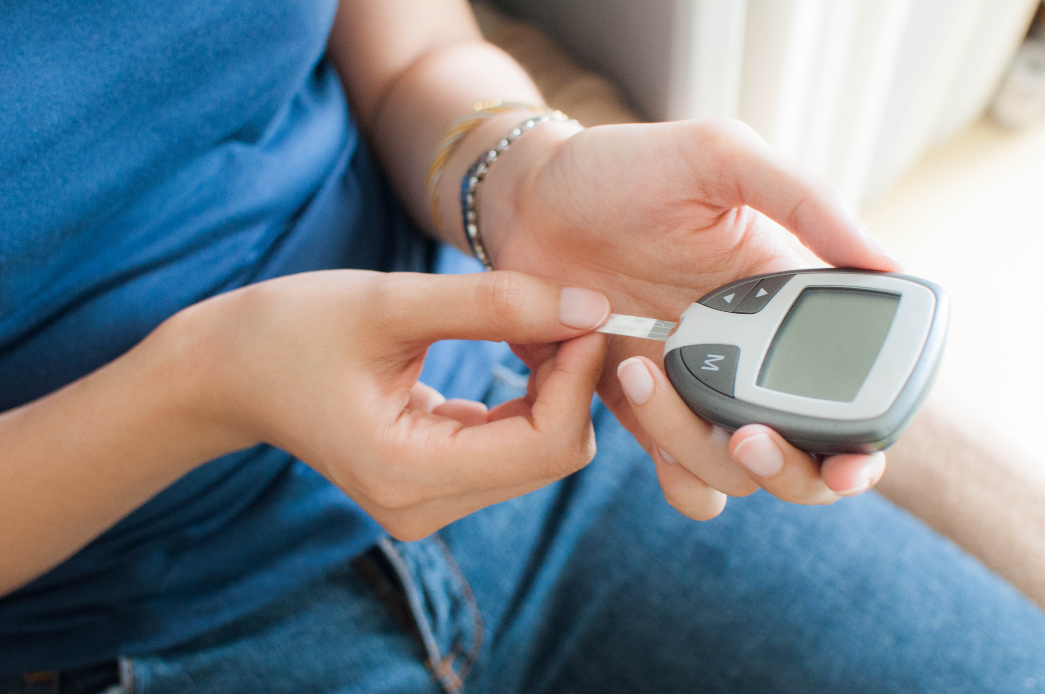 A young woman is using a glucometer to test her blood sugar level (Getty Images)