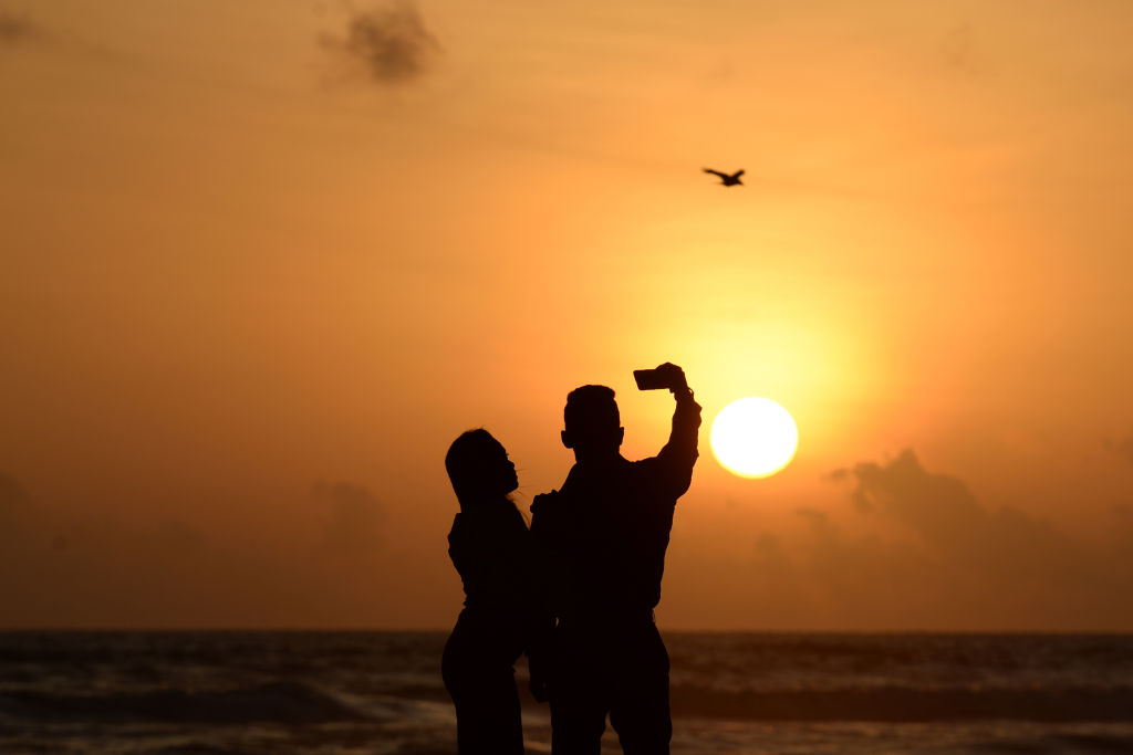 A couple takes a selfie at the beach as the sun sets in the Sri Lankan capital Colombo on July 4, 2019. (LAKRUWAN WANNIARACHCHI/AFP via Getty Images)