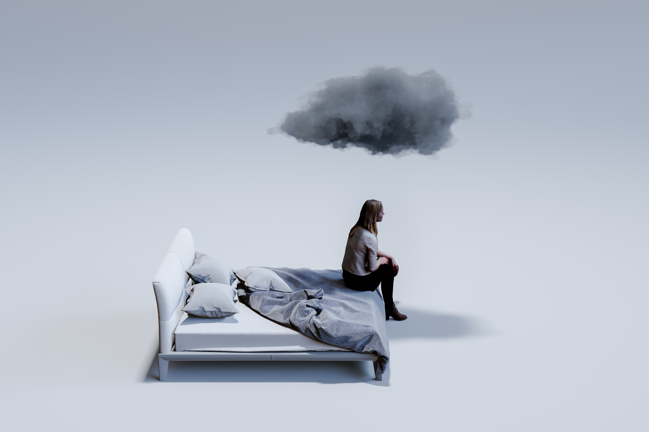Sad mid adult woman sitting on corner of double bed with dark cloud above head.