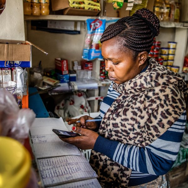 Janeffer Wacheke, co-owner of a fresh-vegetable stall, checks her mobile phone for a purchase order of vegetables and fruits made to Twiga Foods Ltd., while on her stall in Nairobi, Kenya, on June 11, 2018. Wacheke's fresh-vegetable stall in Nairobi uses technology that's helping crack a problem Kenyan banks have so far failed to solve -- measuring the creditworthiness of traders in the country's $20 billion informal economy.
