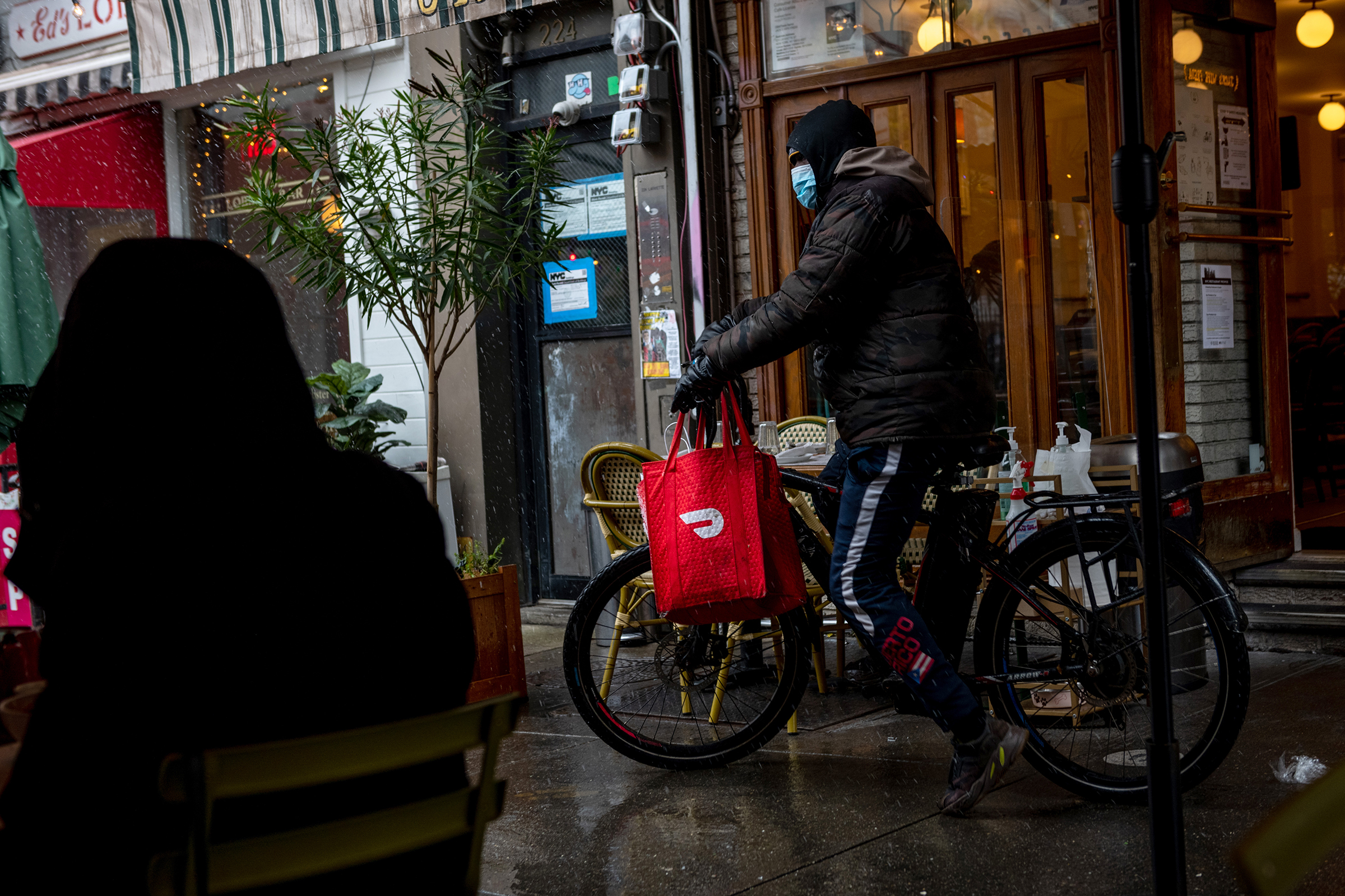 A DoorDash delivery driver riding a bicycle picks up food from Jack's Wife Freda during the first snow of the season on December 09, 2020 in New York City. (Alexi Rosenfeld—Getty Images)
