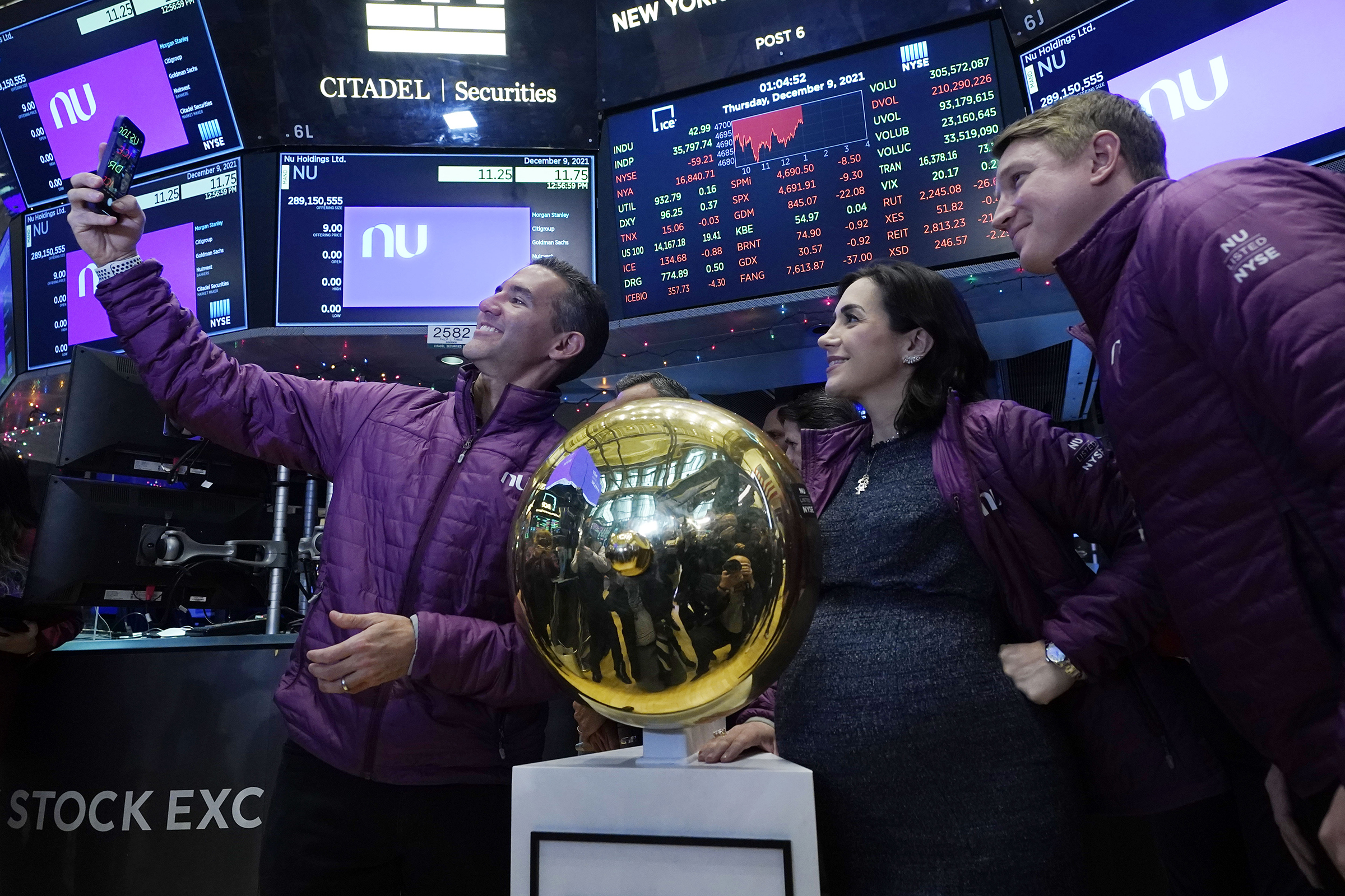 Nubank CEO David Velez, left, takes a selfie photo with his company's co-Founders Cristina Junqueira, and Edward Wible, before he rings the ceremonial first trade bell during his IPO, on the New York Stock Exchange trading floor, Thursday, Dec. 9, 2021. (Richard Drew—AP)