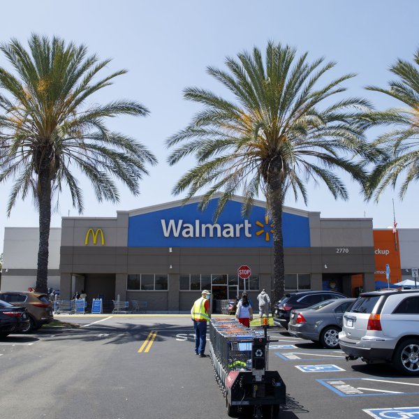 An employee pulls carts towards a Walmart store in Lakewood, California, U.S., on Thursday, July 16, 2020.