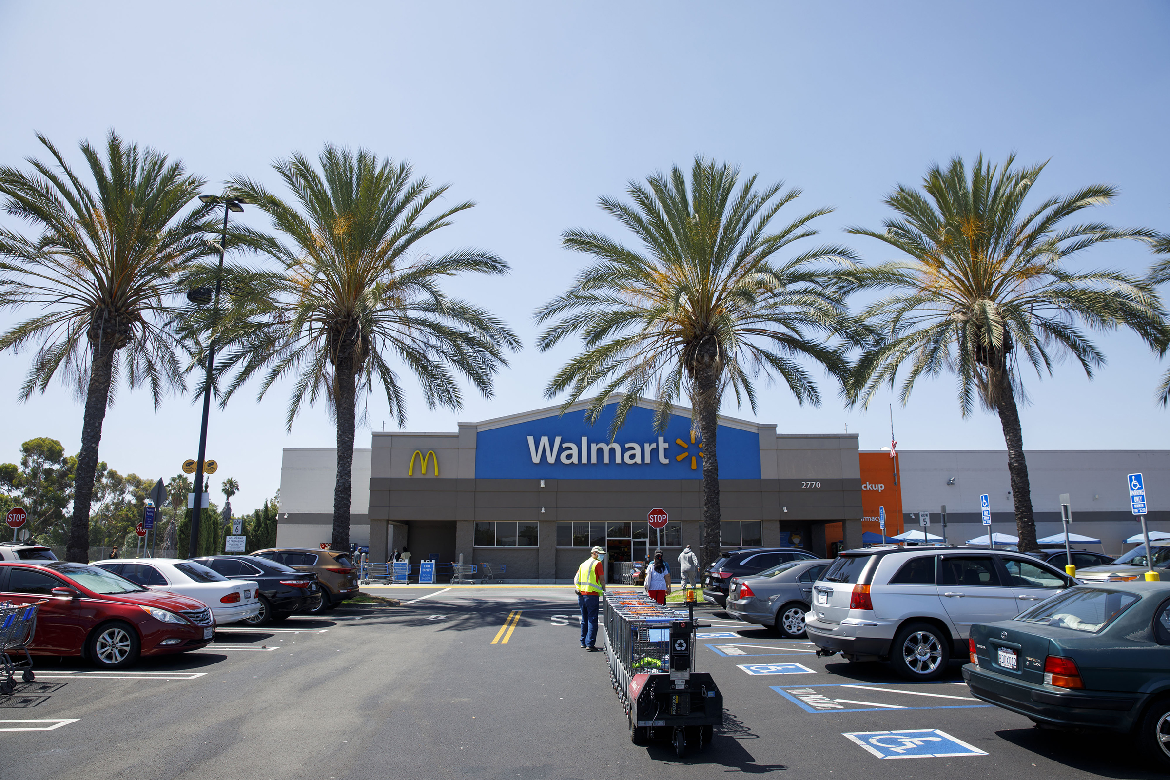 An employee pulls carts towards a Walmart store in Lakewood, California, U.S., on Thursday, July 16, 2020. (Patrick T. Fallon—Bloomberg/Getty Images)