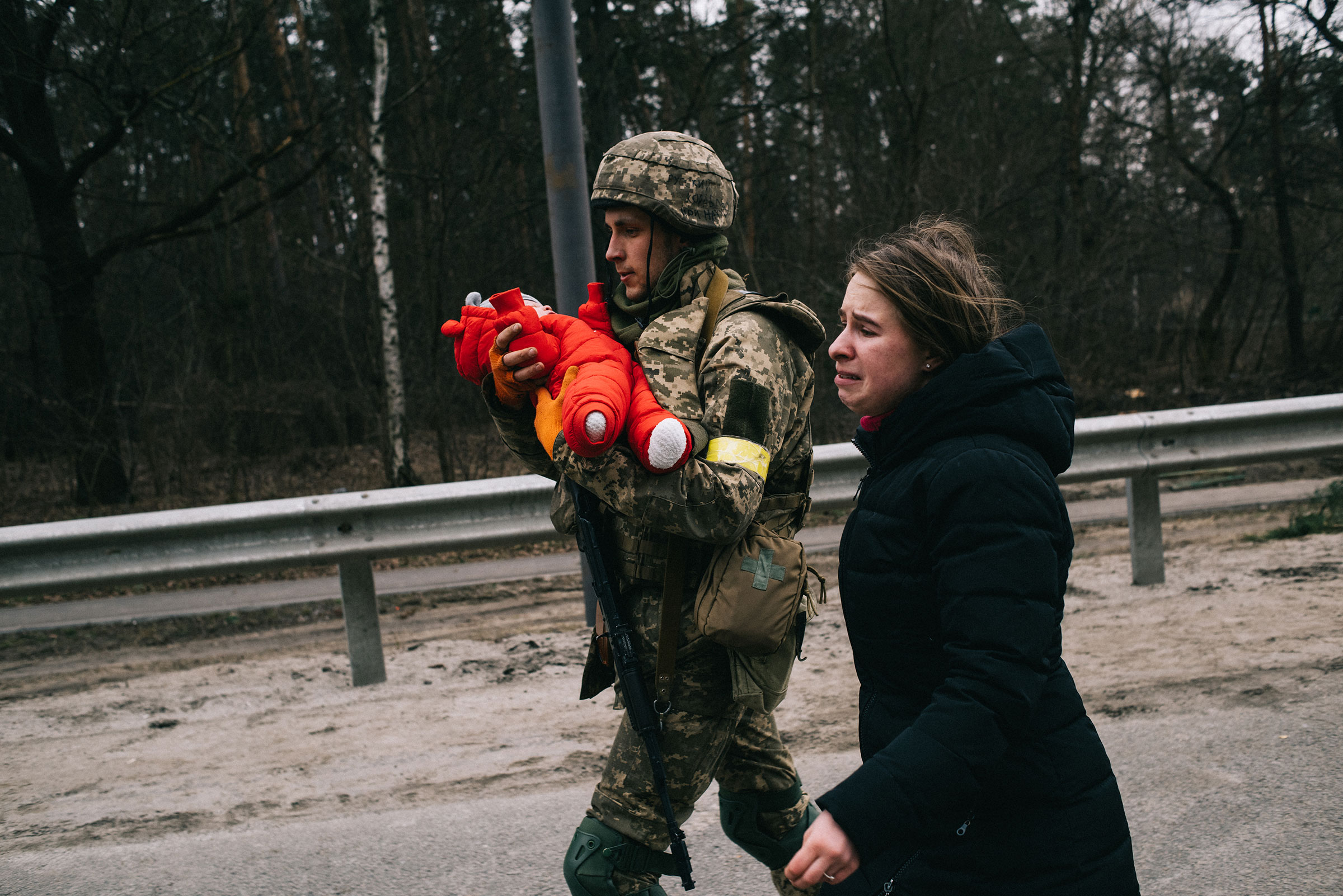 A Ukrainian soldier helps Julia Pavliuk and her daughter Emma evacuate the Kyiv suburb of Irpin, which Russian forces have tried to seize as part of their push to encircle the capital om March 5 (Maxim Dondyuk)