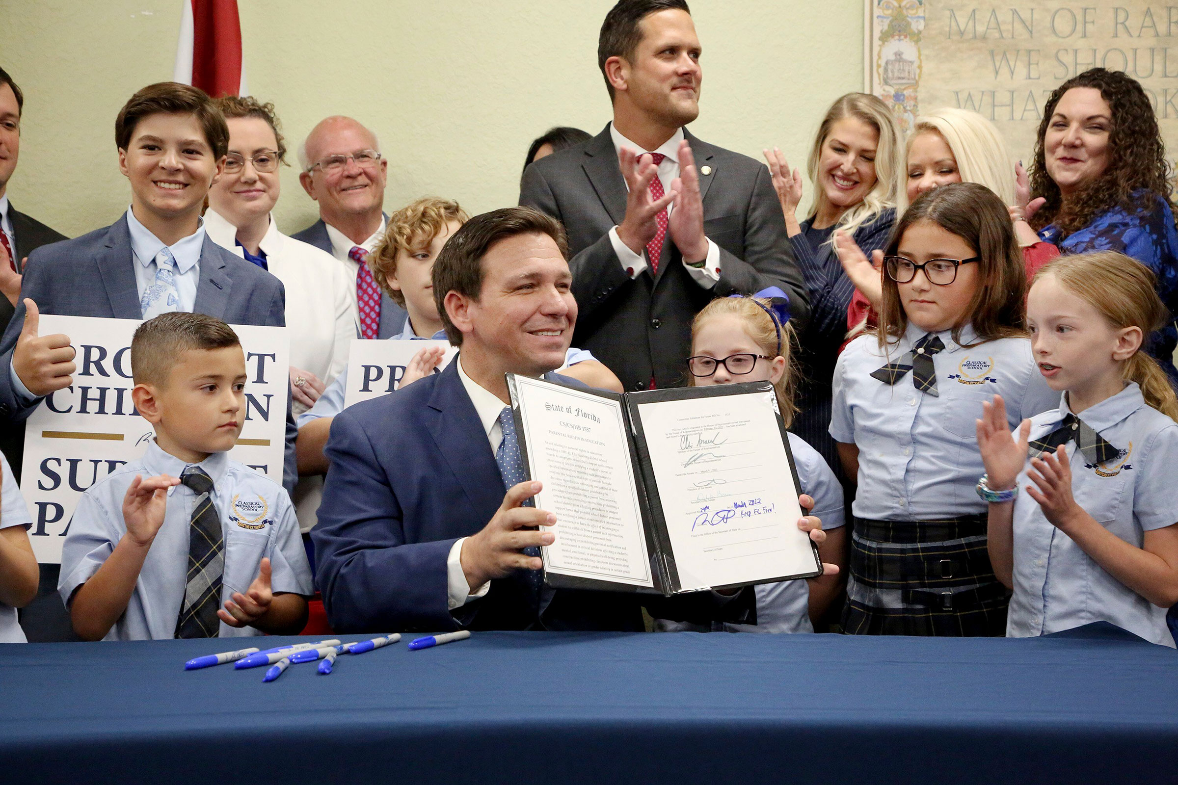 Florida Gov. Ron DeSantis displays the signed Parental Rights in Education, aka the Don't Say Gay bill, flanked by elementary school students during a news conference at Classical Preparatory school in Shady Hills, Fla. on March 28, 2022. (Douglas R. Clifford—AP)