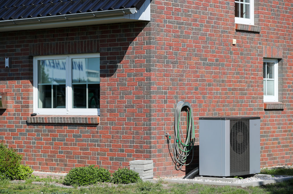 A heat pump is located next to a prefabricated house model from Helma-Eigenheimbau AG in Schkeuditz, Germany, on April 30 2019. (Jan Woitas/picture alliance—Getty Images)