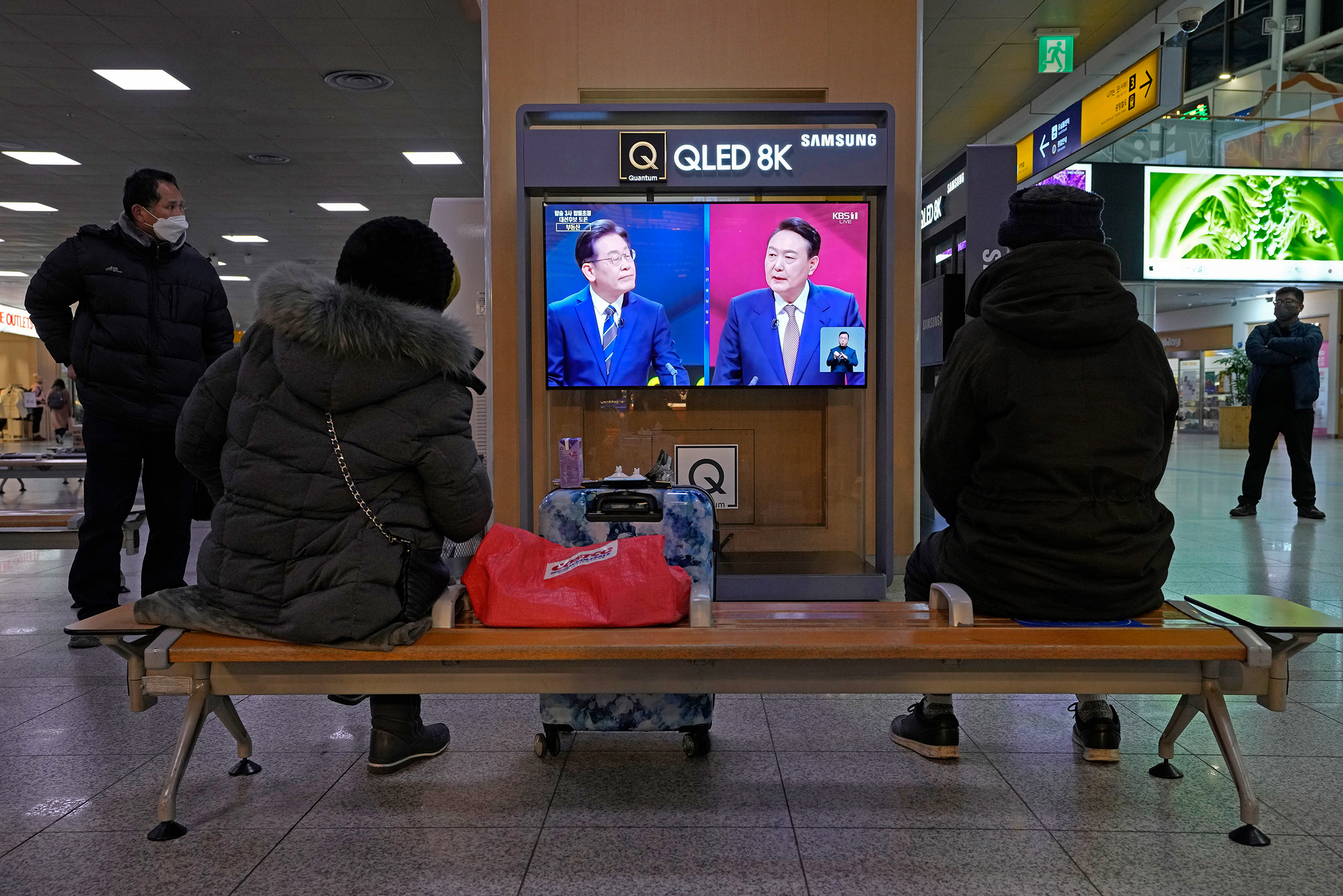 People watch a live broadcast of Lee Jae-myung, of the ruling Democratic Party, and Yoon Suk-yeol, of the main opposition People Power Party during a presidential debate for the upcoming March 9 presidential election at the Seoul Railway Station on Feb. 3 (Ahn Young-joon—AP)