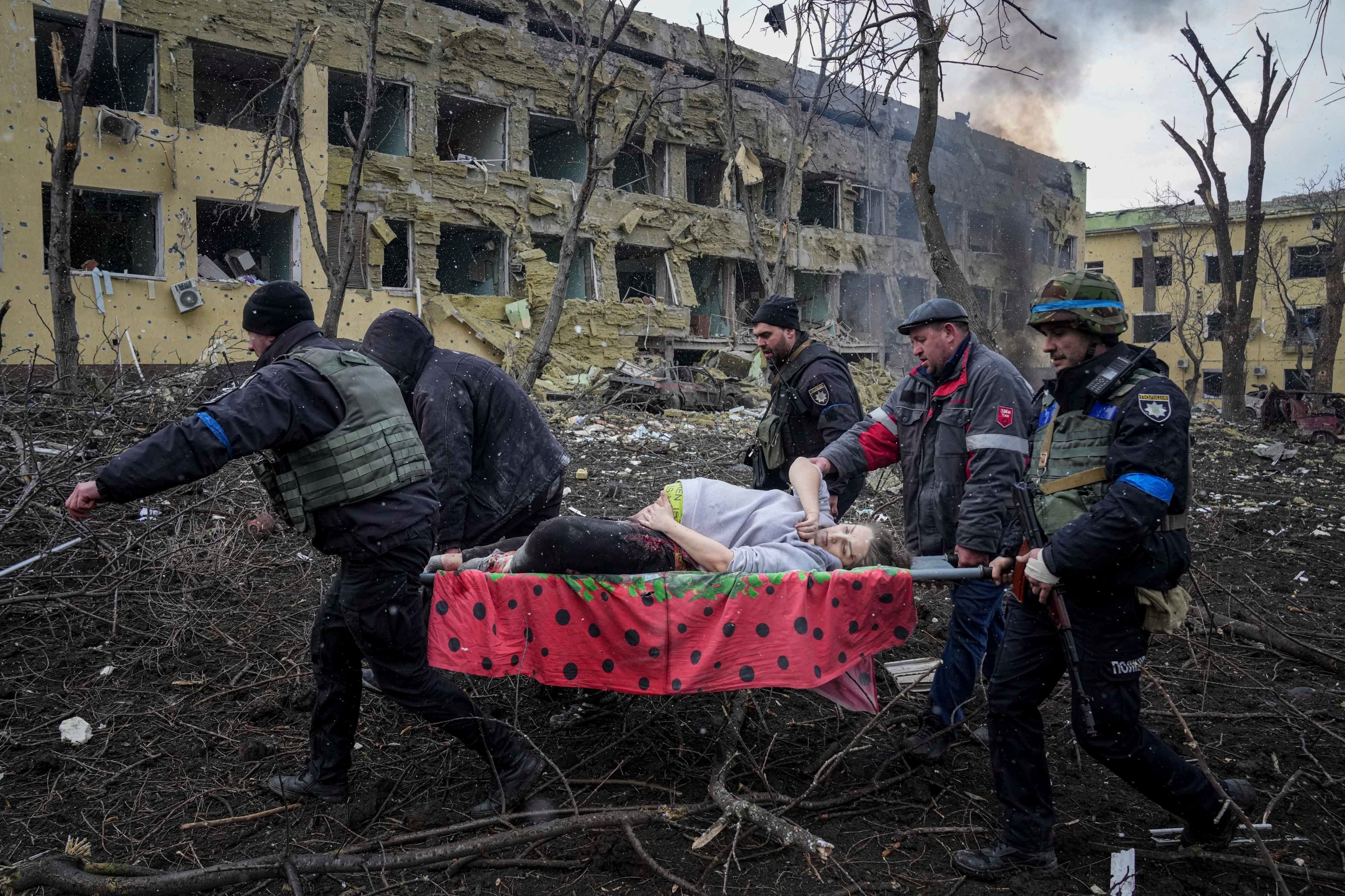 Ukrainian emergency employees and volunteers carry an injured pregnant woman from a maternity hospital that was damaged by shelling in Mariupol, Ukraine, March 9, 2022. The woman and her baby died after Russia bombed the maternity hospital where she was meant to give birth. (Evgeniy Maloletka—AP Photo)