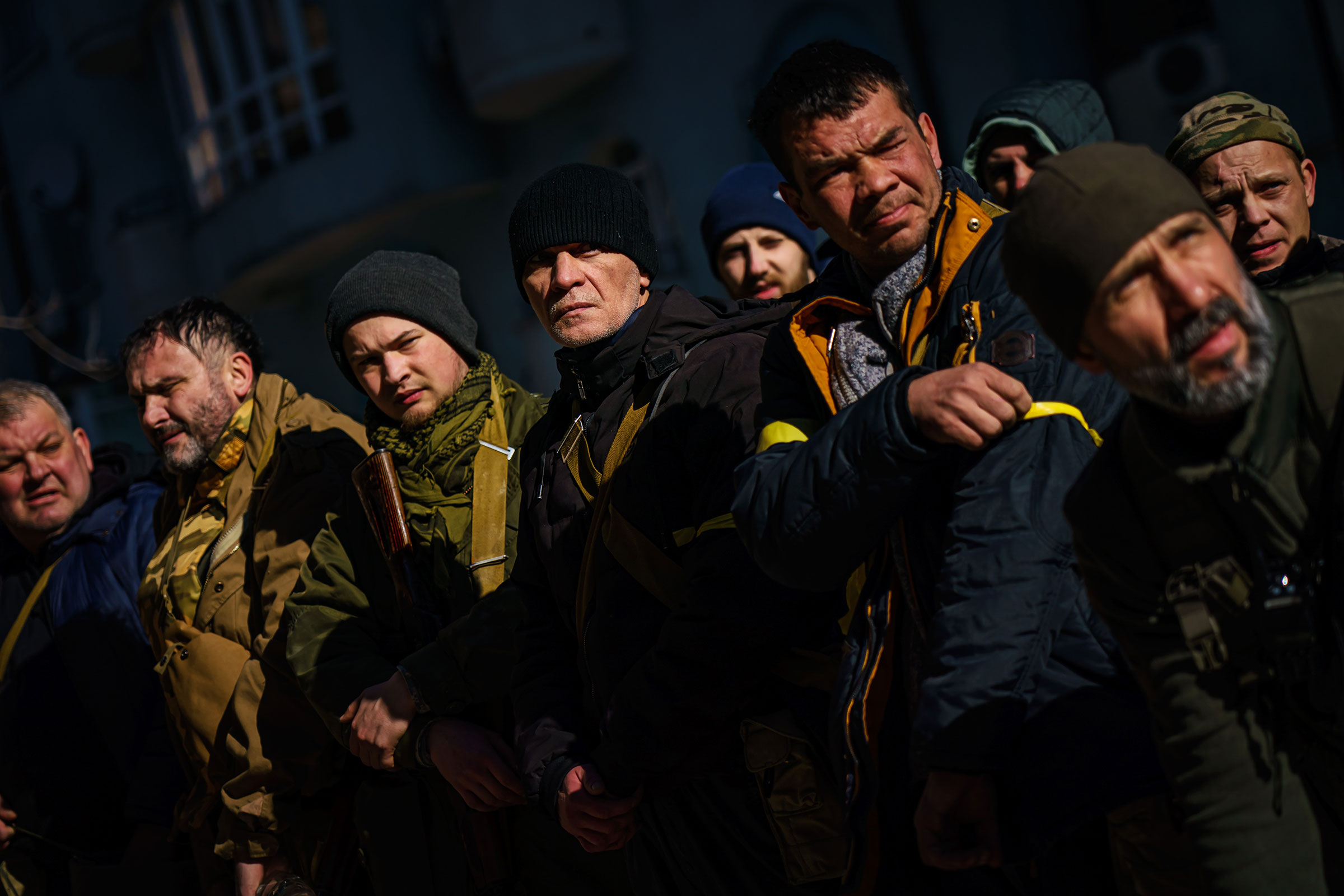 Volunteers for the Territorial Defense Forces stand in formation, check their weapons, put on yellow armbands, get marching orders, and ship out to their posts to defend Kyiv on Feb. 28. (Marcus Yam—Los Angeles Times/Getty Images)
